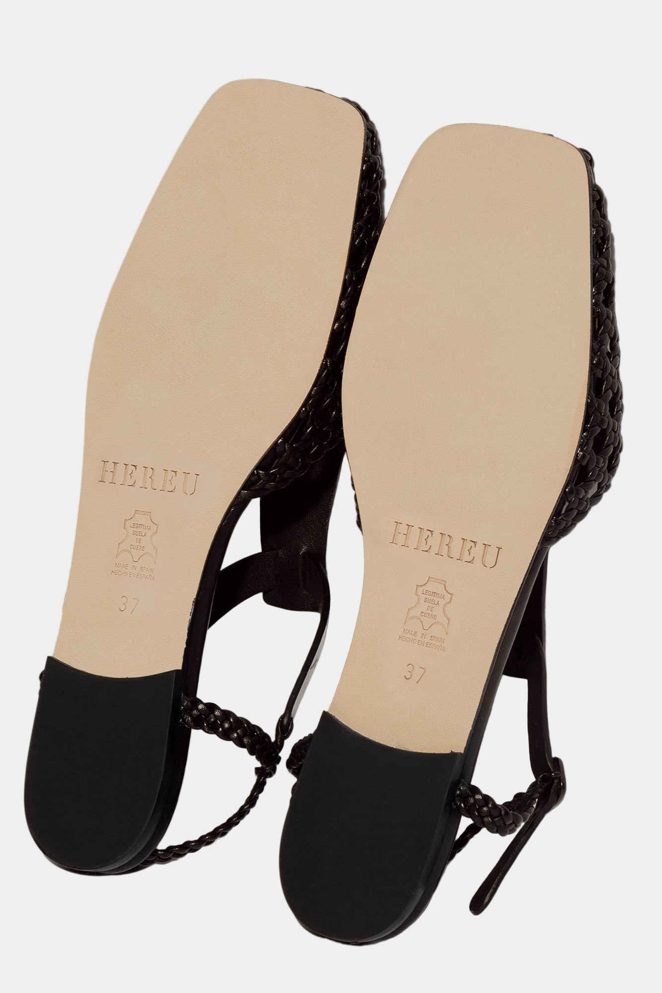 Black sandals with braided design on a white background. View of sole with Hereu branding embossed into the leather.