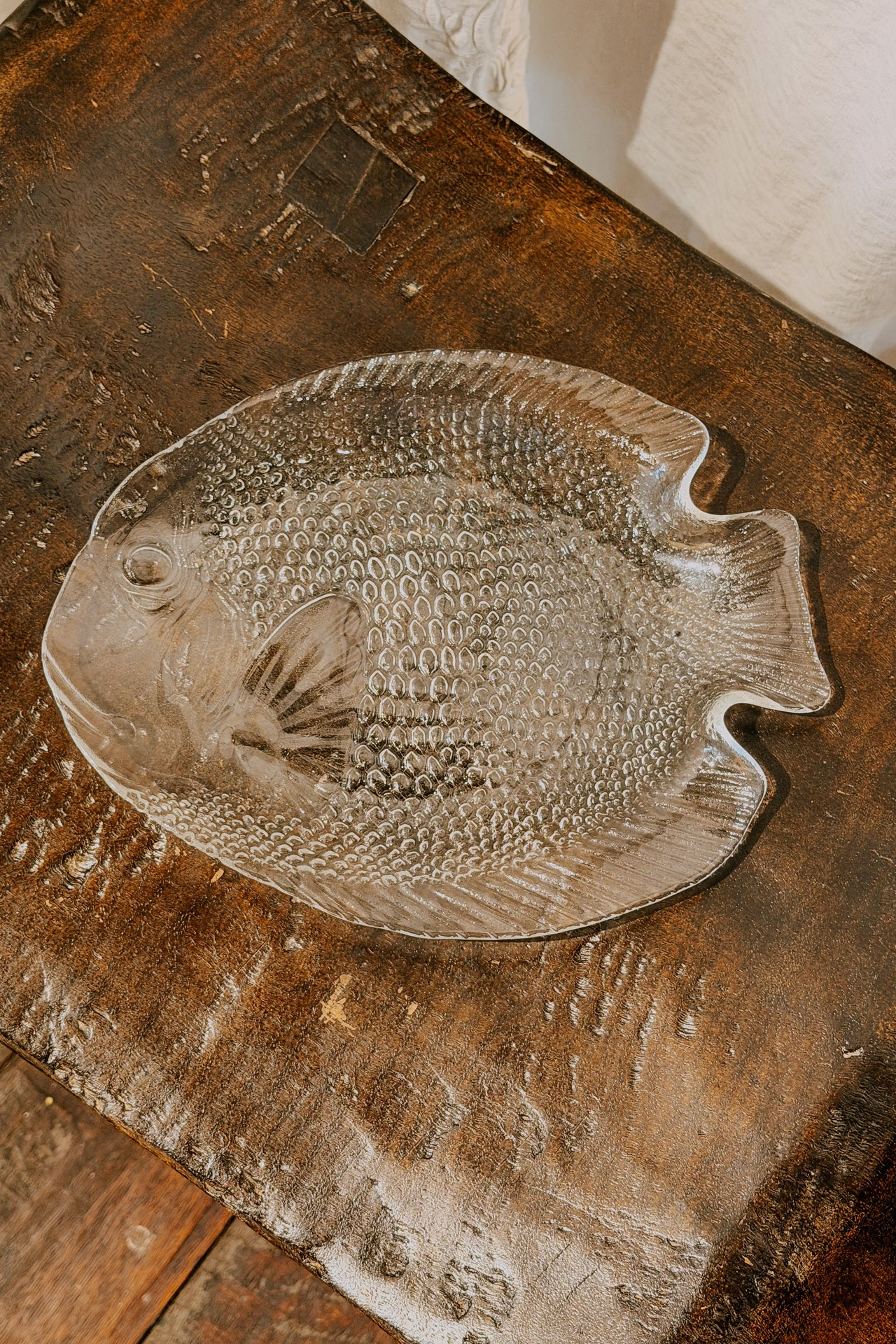 Decorative glass fish plate displayed on a wooden surface