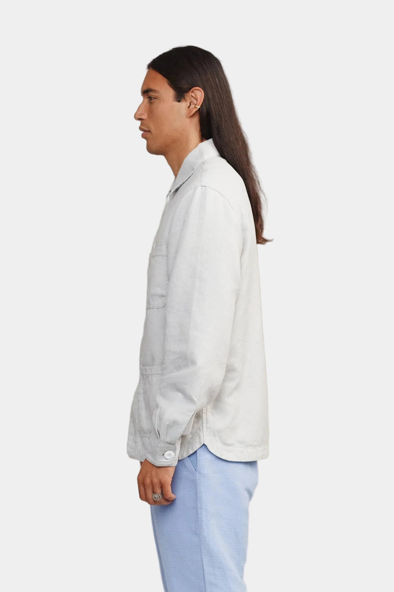 Person wearing a light gray shirt and light blue pants against a plain background