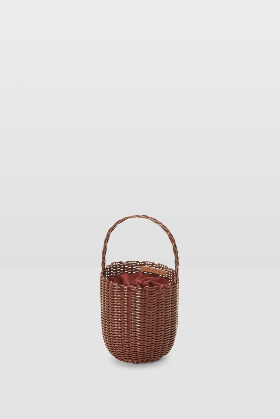 Woven basket with handle on a light gray background