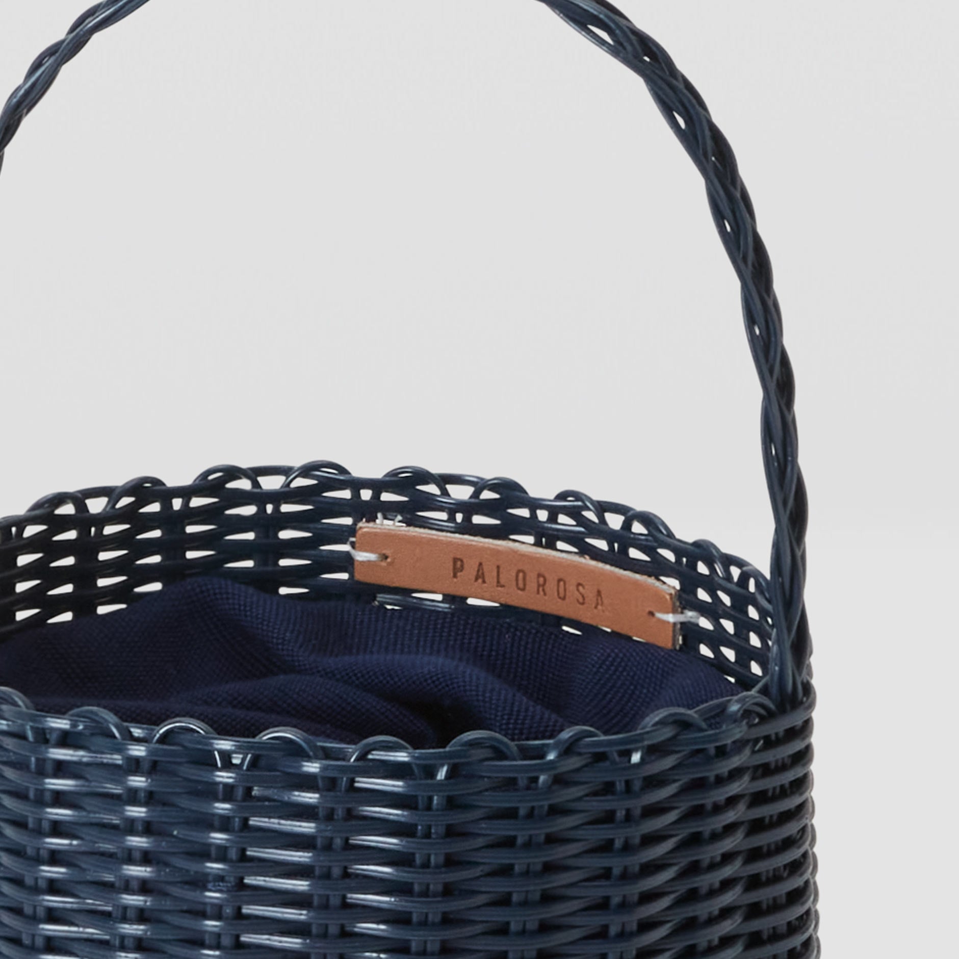 Navy woven basket with a brown label on a light gray background
