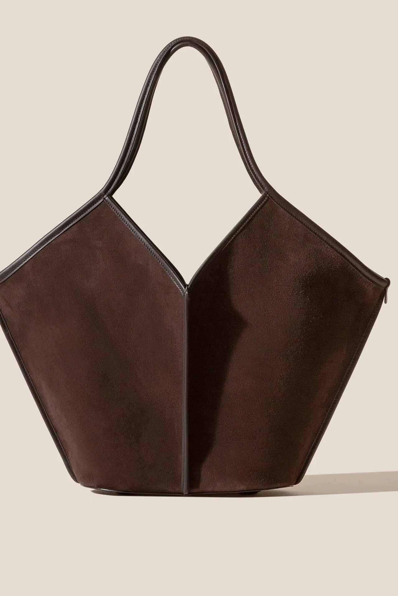 Brown handbag with a unique geometric design on a beige background