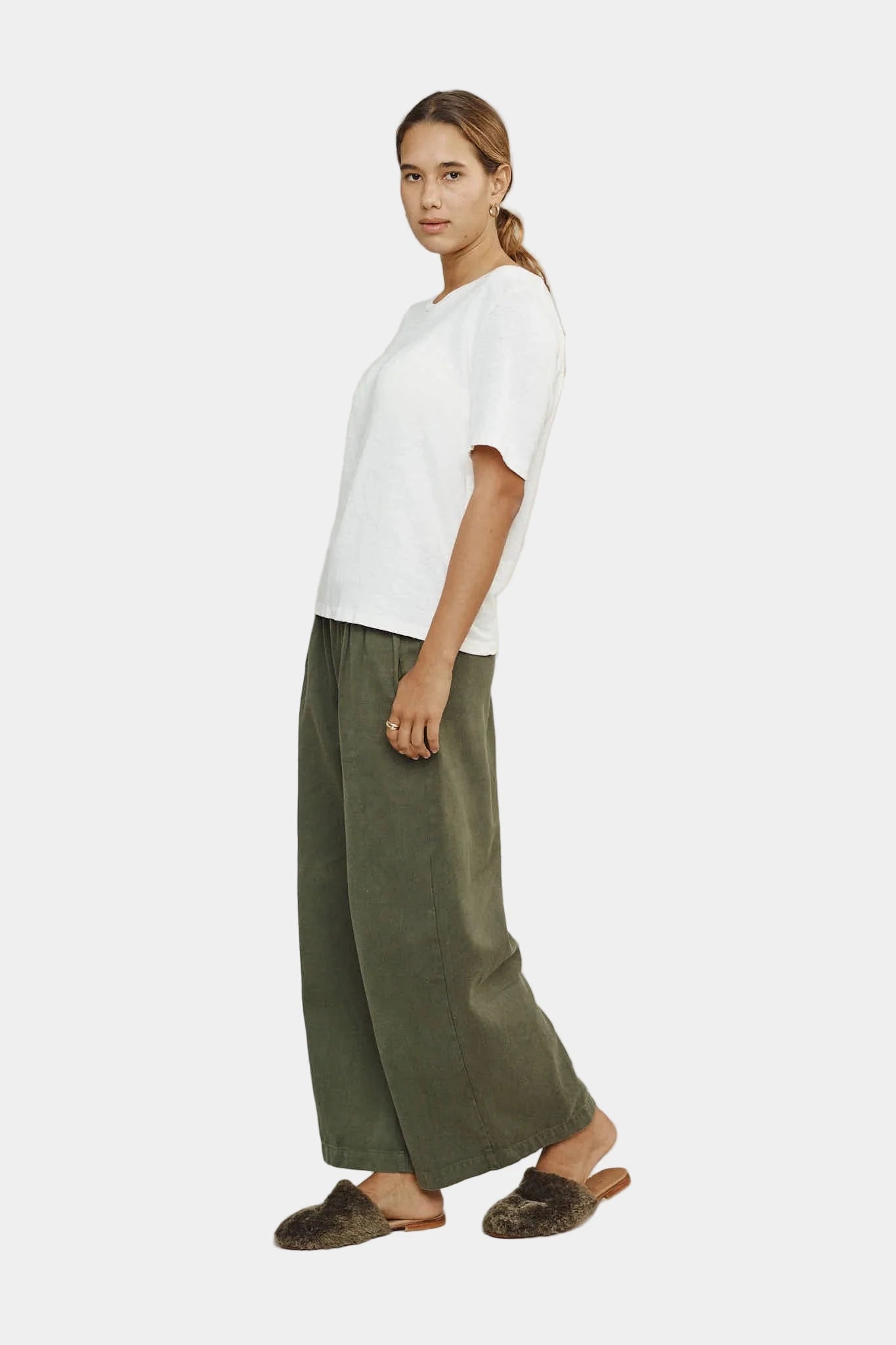 person wearing white t-shirt and green pants on a plain background