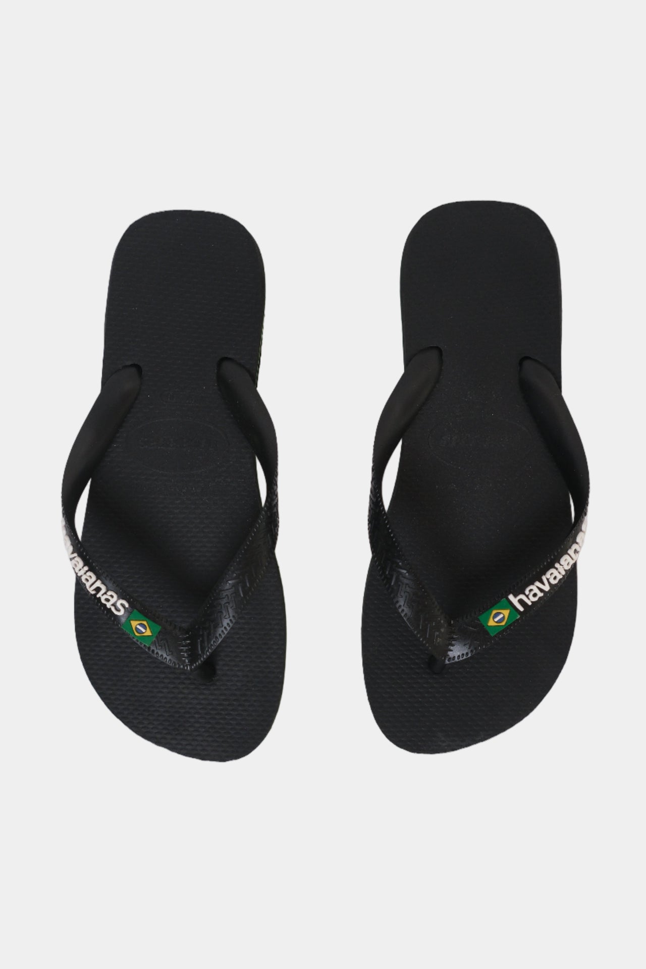 A pair of black Havaianas flip-flops with a green and white Brazil flag and stripe design around the sole.