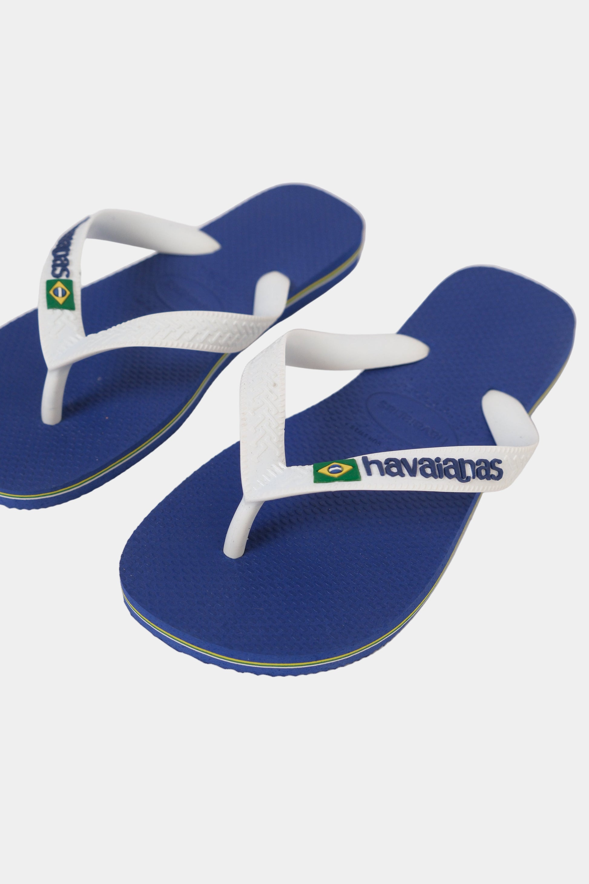 Blue and white Havaianas flip-flops with brand logo on a light gray background