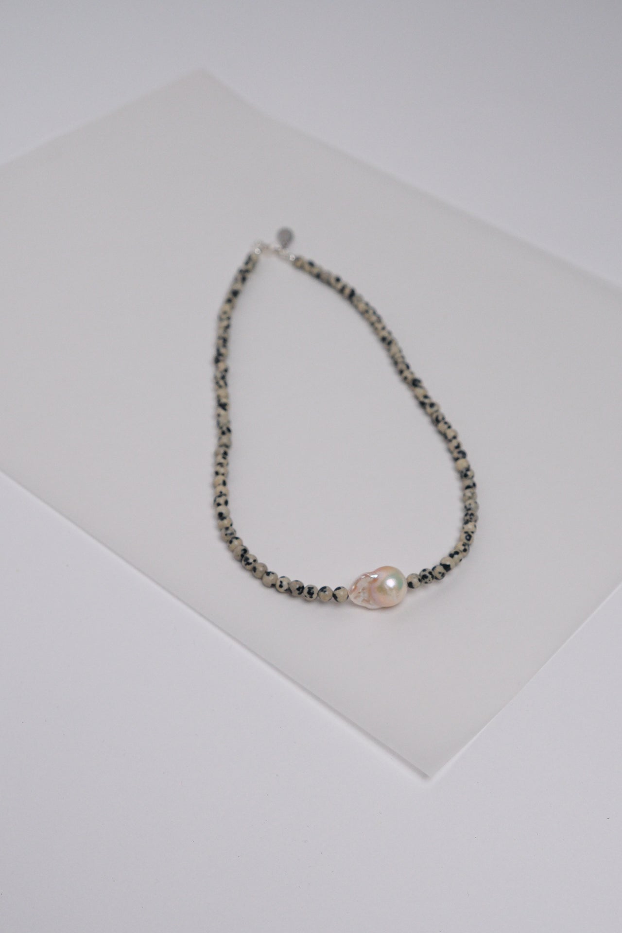 A necklace with Dalmatian Jasper semi-precious stones and a single baroque fresh water pearl.
