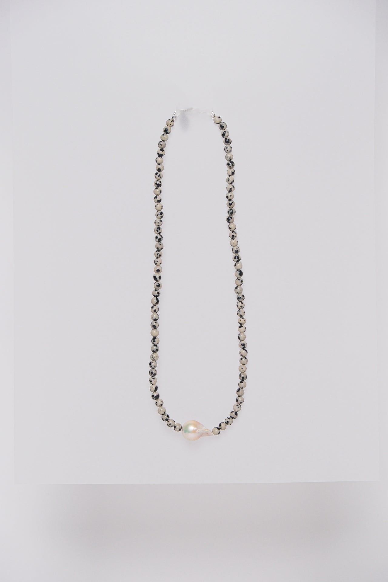 A necklace with Dalmatian Jasper semi-precious stones and a single baroque fresh water pearl.