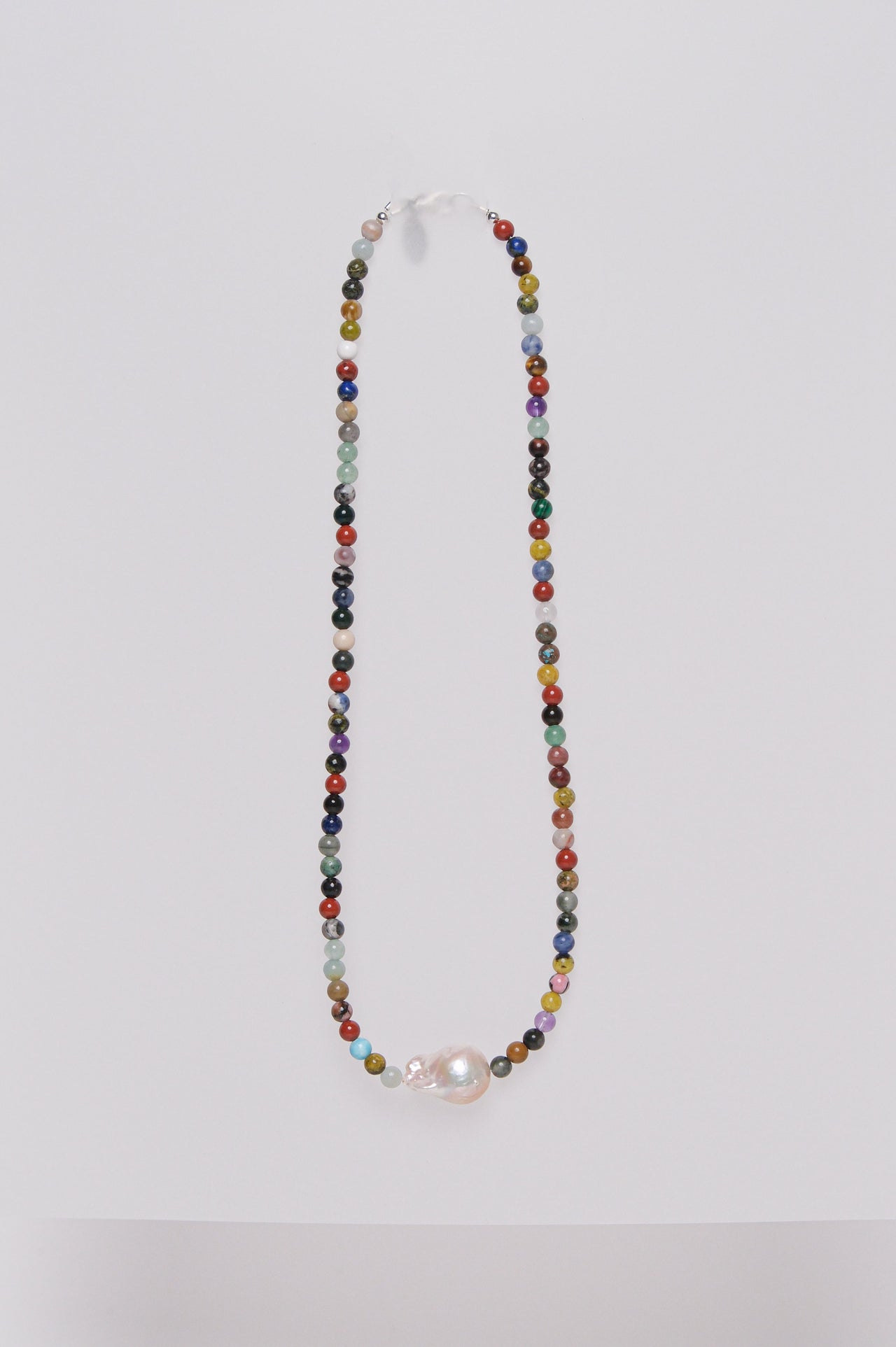 A multicolored beaded necklace with a single baroque fresh water pearl at the center, displayed against a white background.