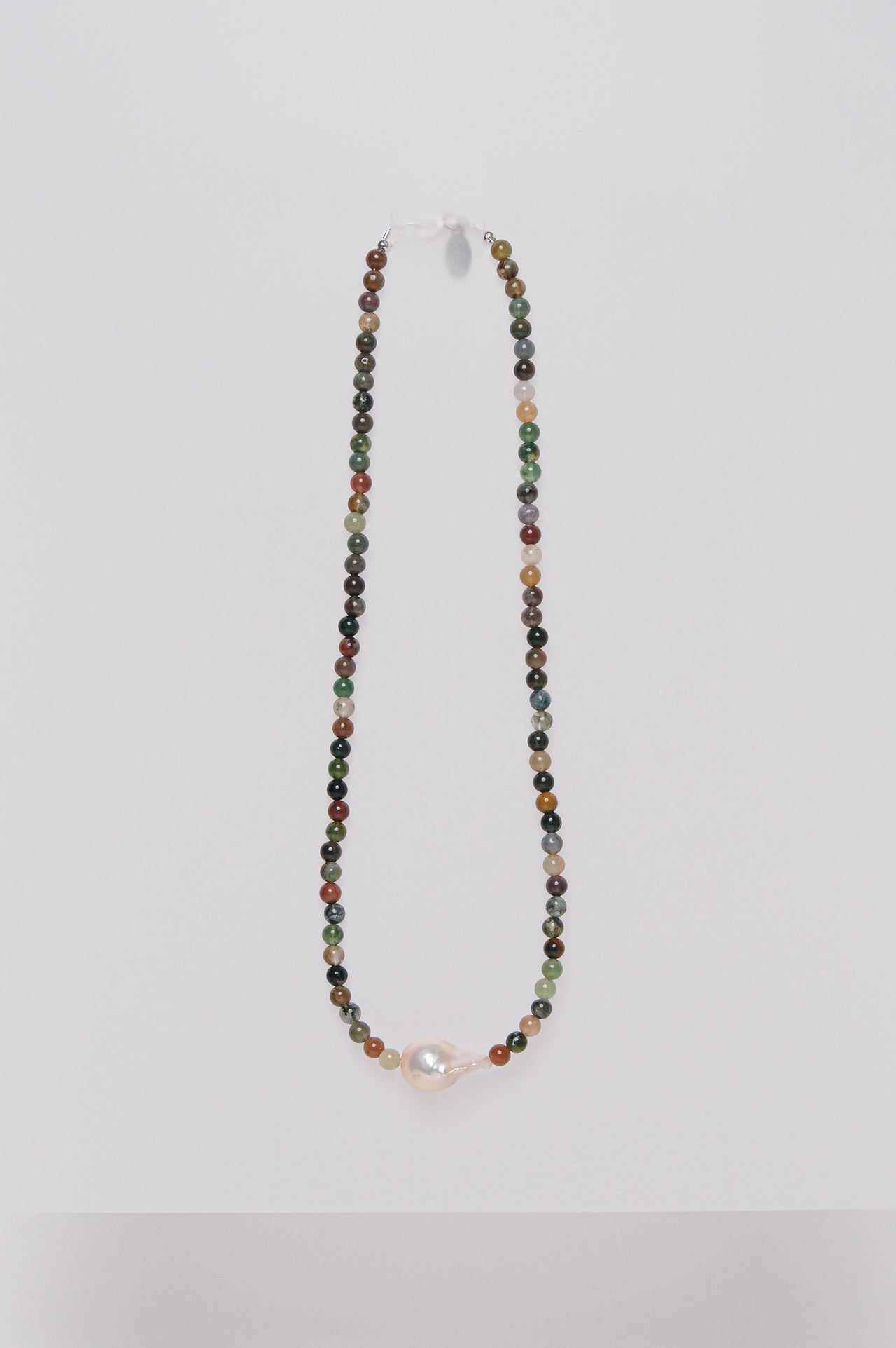 A beaded necklace with multicolored semi-precious stones and a single baroque fresh water pearl, displayed against a white background.
