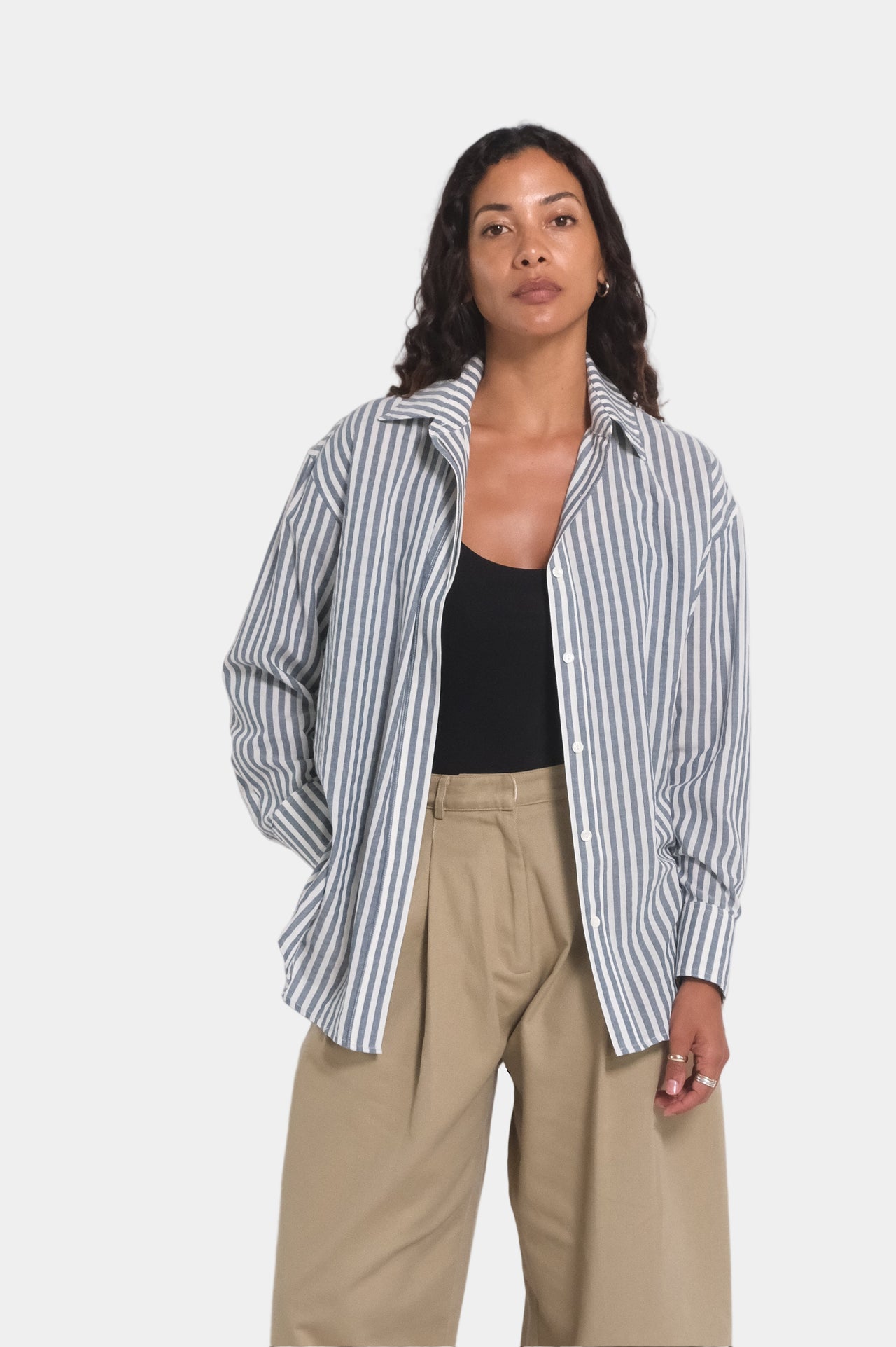 a women wearing a grey blue and white stripe shirt and beige trousers with a black singlet