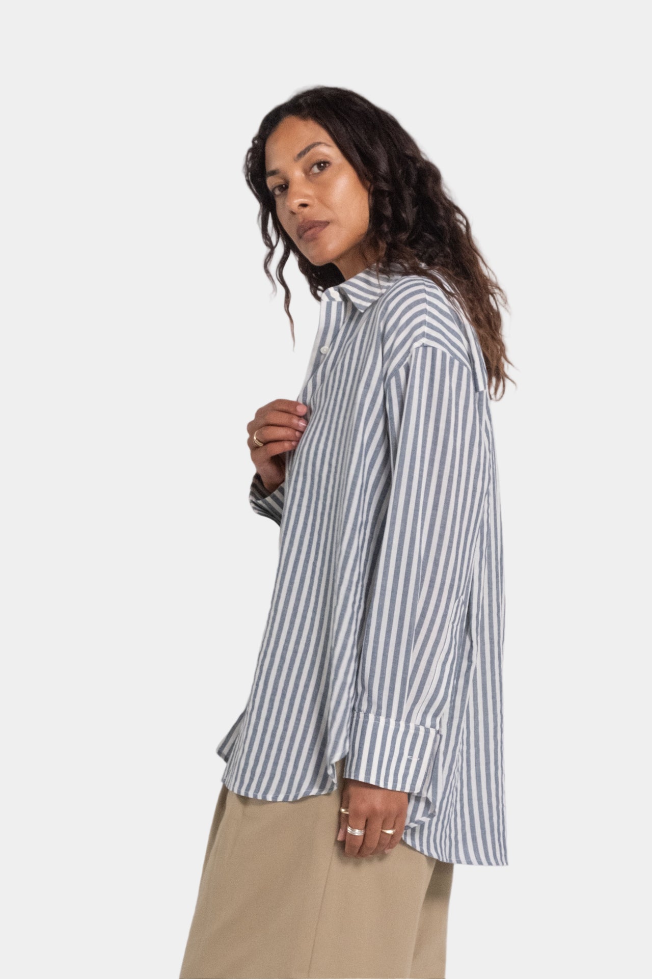 a women wearing a grey blue and white stripe shirt and beige trousers with a black singlet