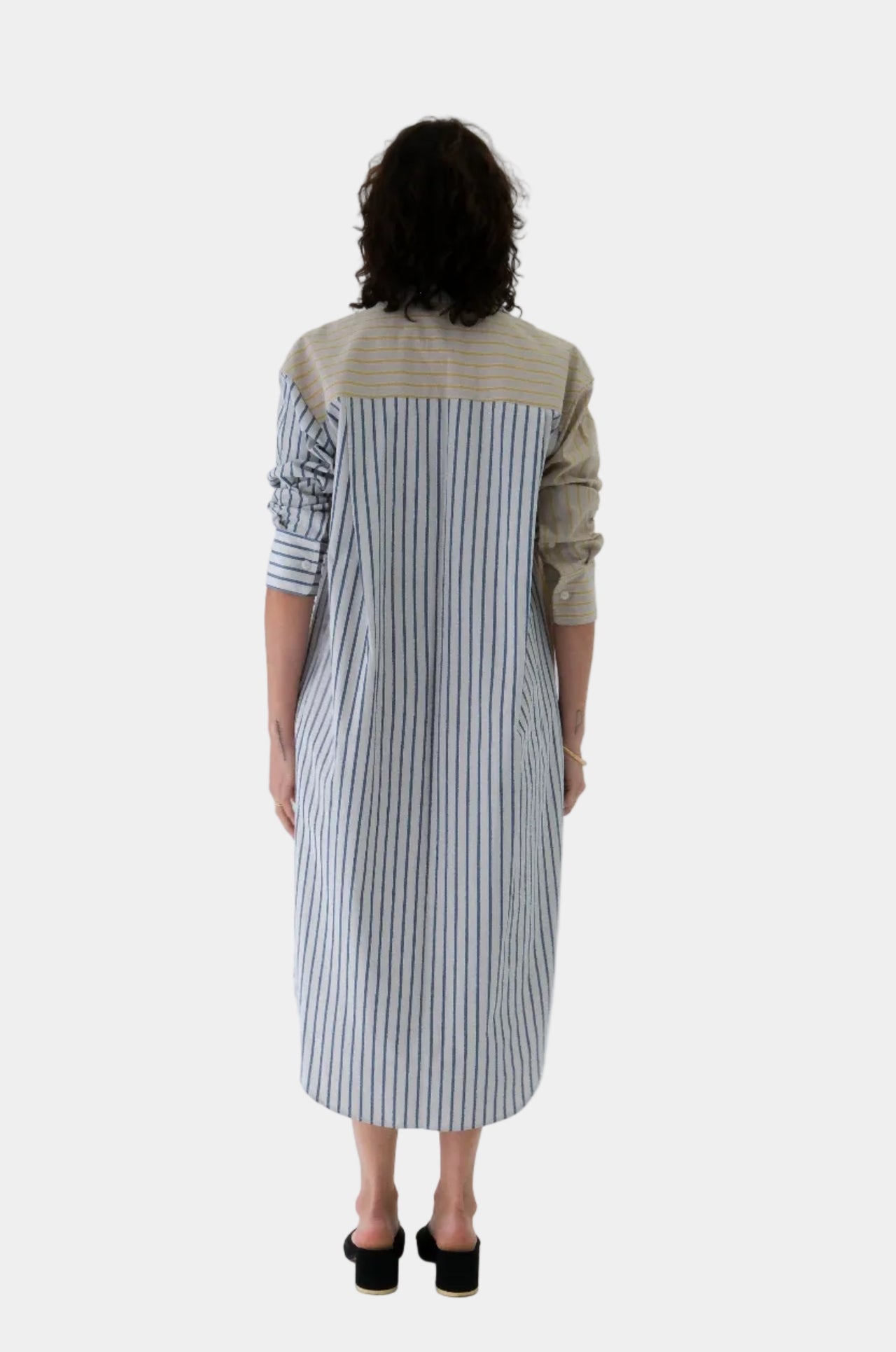 Woman wearing a two-tone dress with beige and striped patterns on a white background