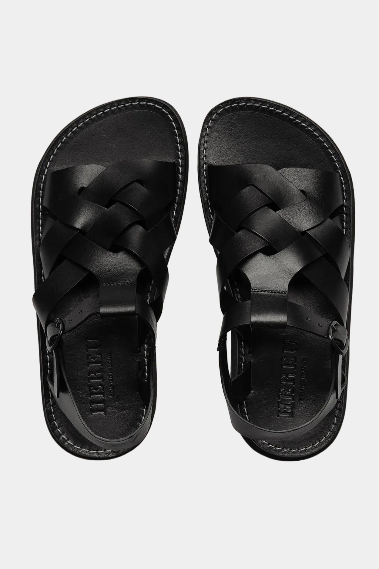 A pair of black Beltra sandals by Hereu, constructed with interwoven leather straps and a foam sole. Viewed from above