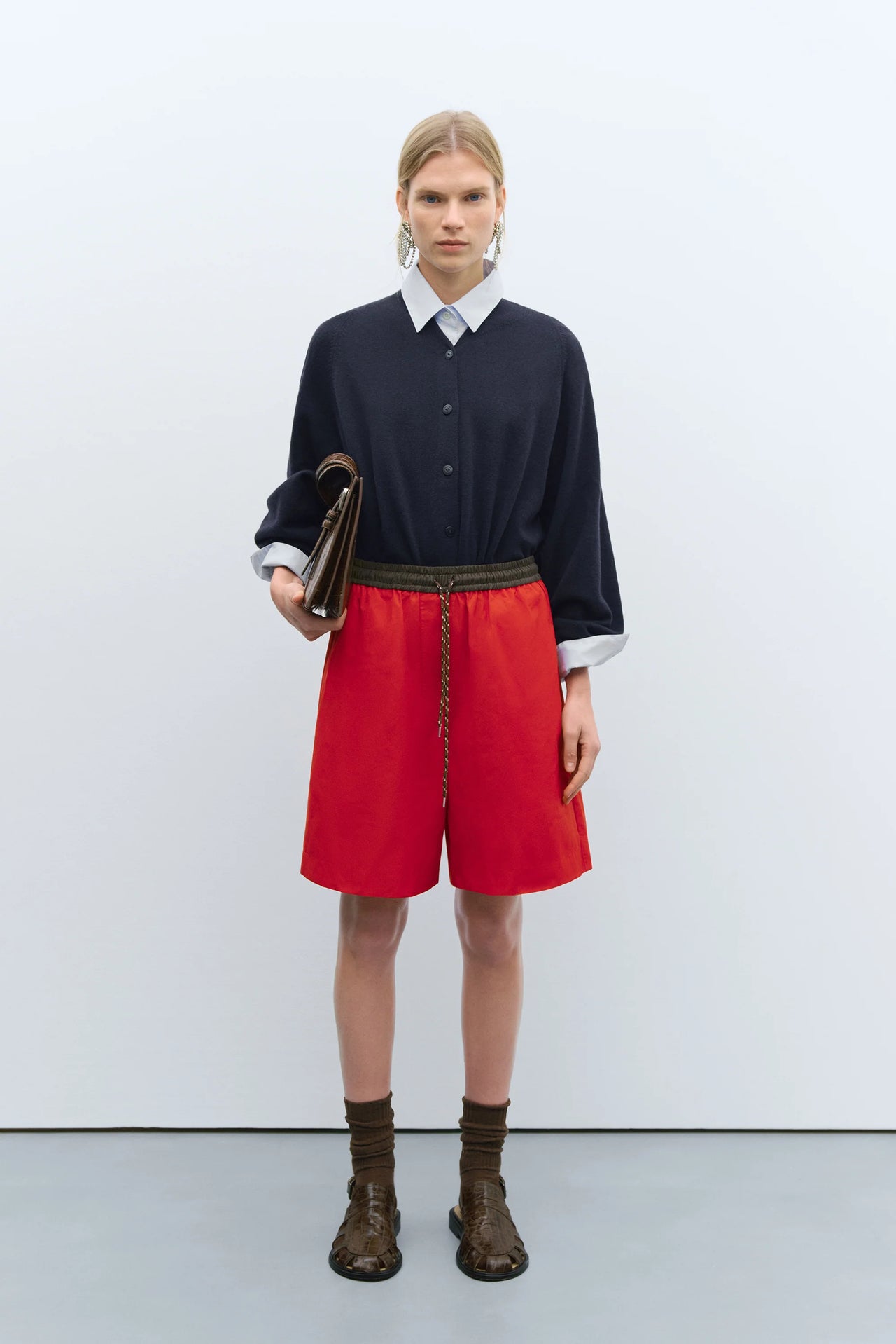 Person wearing a red skirt with a black top and brown bag on a white background