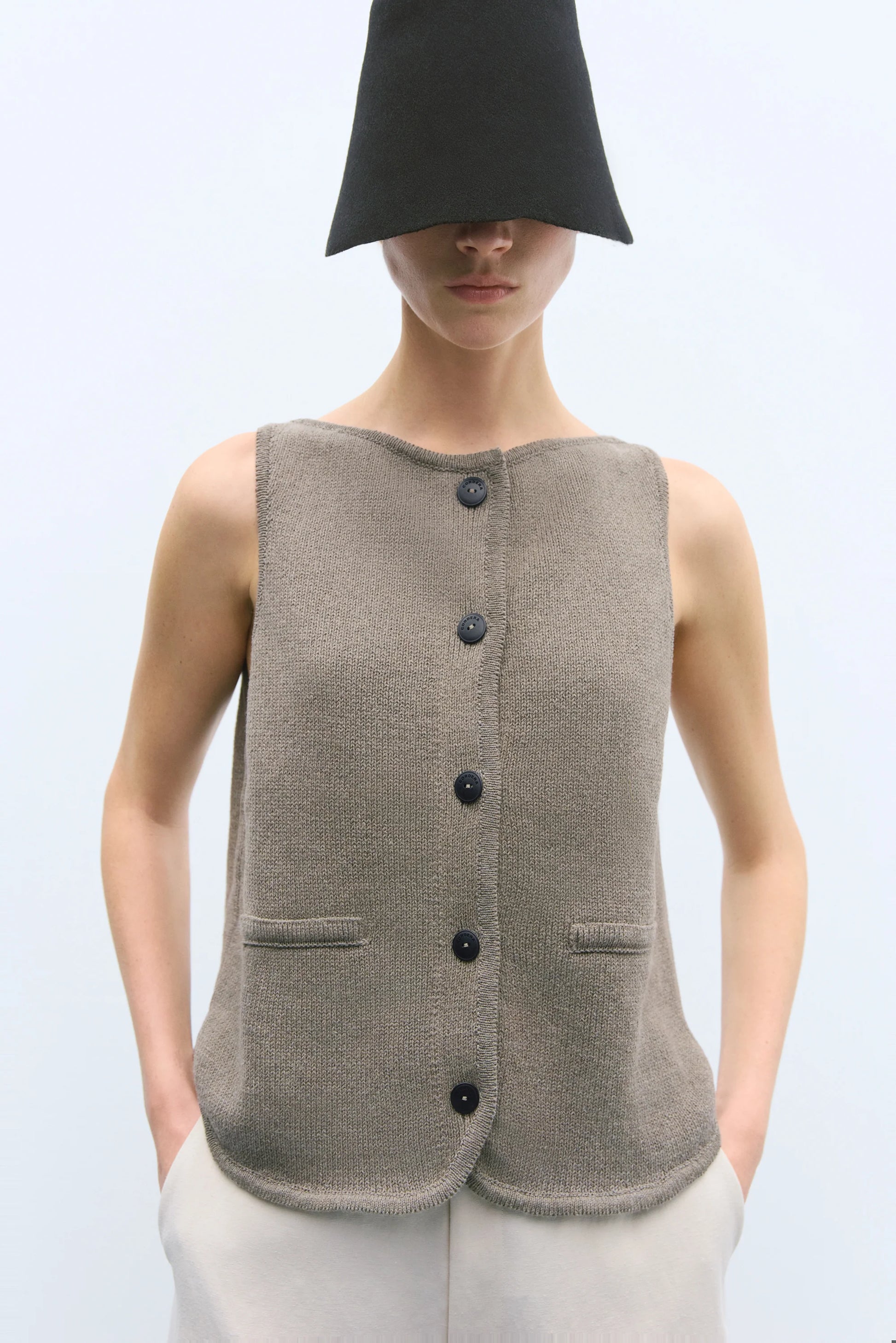 Person wearing a brown button-up vest on a light gray background