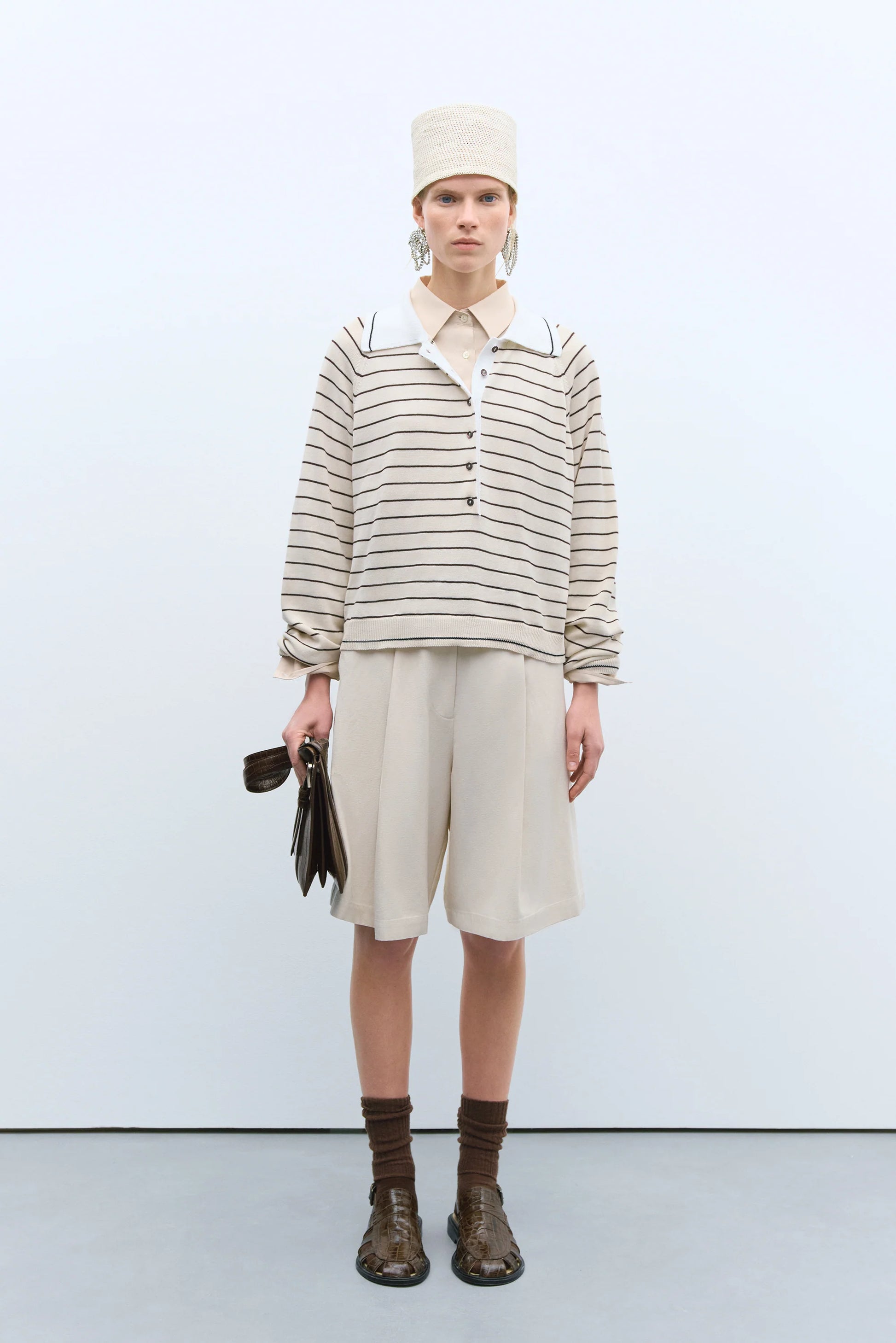 Person wearing a striped shirt, beige skirt, and brown boots against a white background