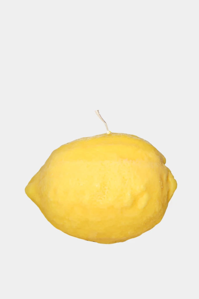 Yellow lemon-shaped candle on a white background