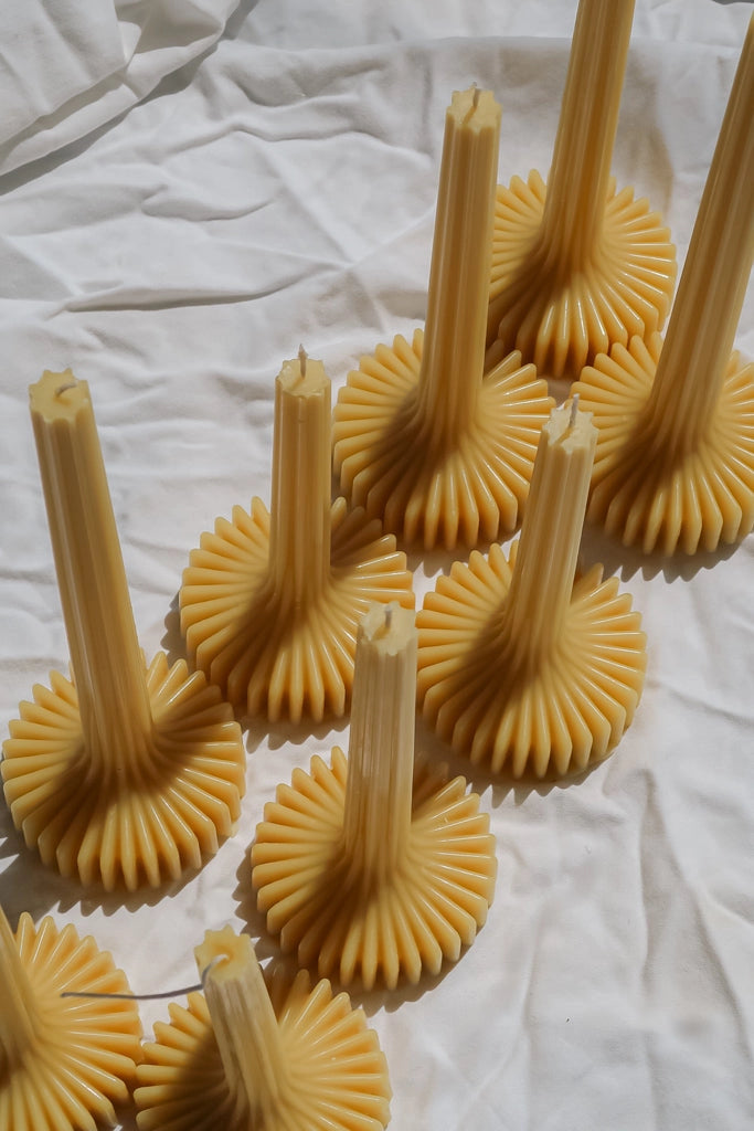 Ribbed beeswax dinner candles on crinkled fabric