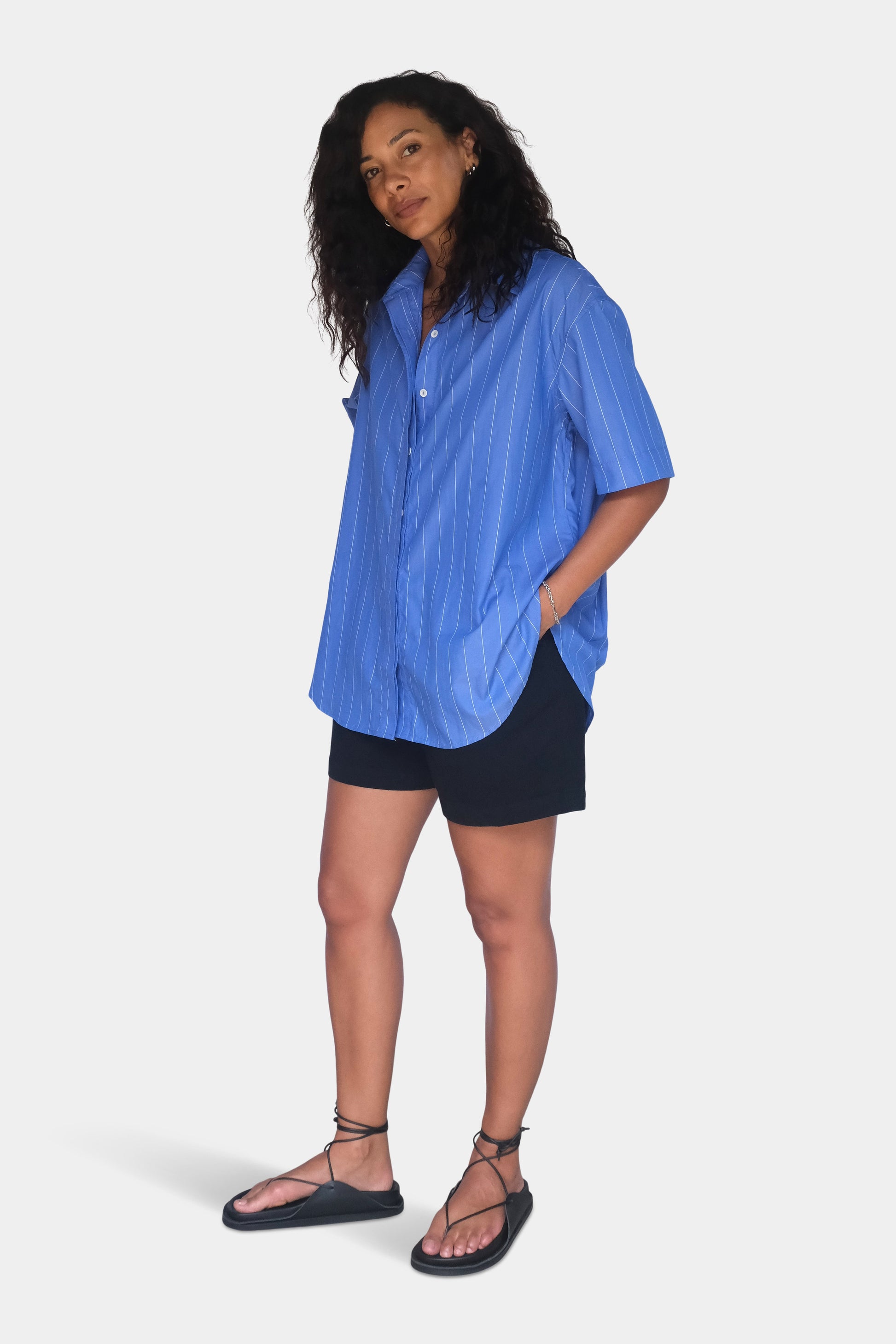 Woman wearing a blue shirt and black shorts on a white background