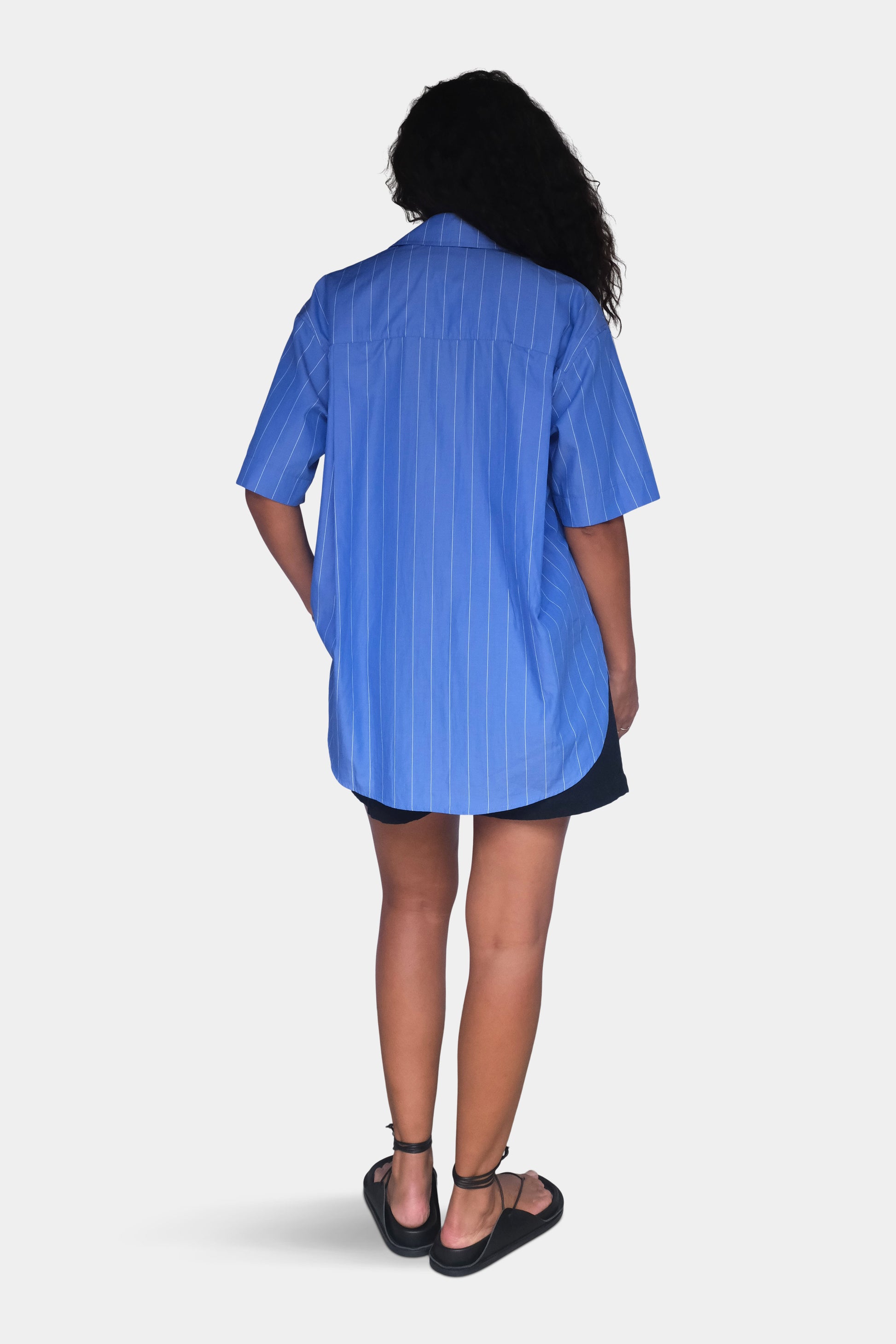 Person wearing a blue striped shirt on a white background viewed from the back