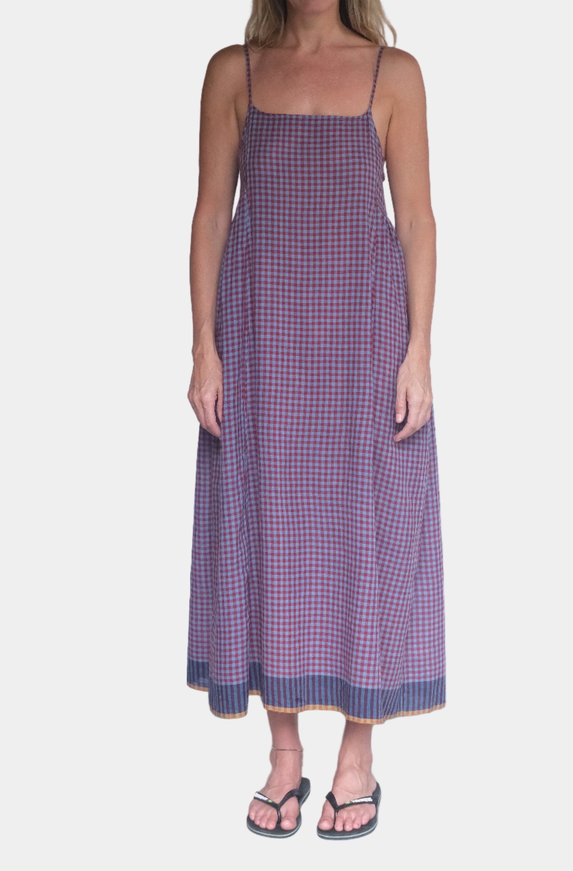 Woman wearing a purple checkered dress standing against a white backdrop