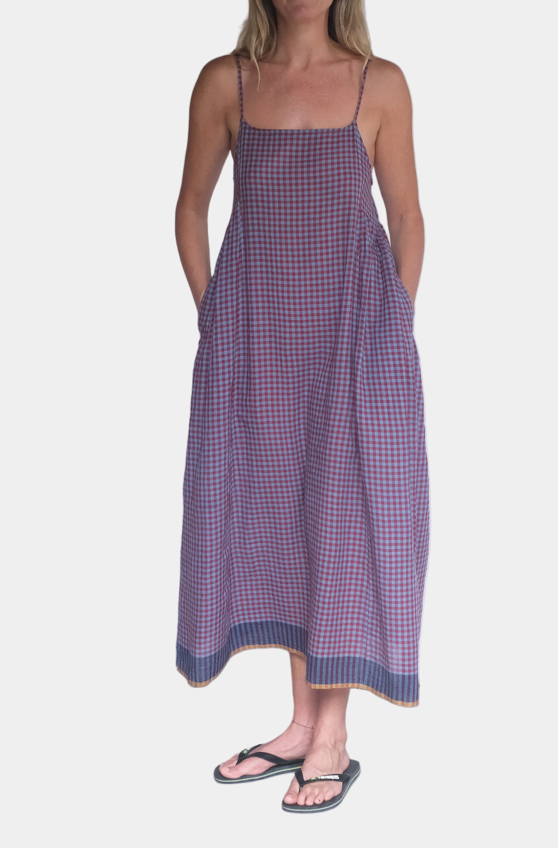 Woman wearing a purple checkered dress standing against a white background