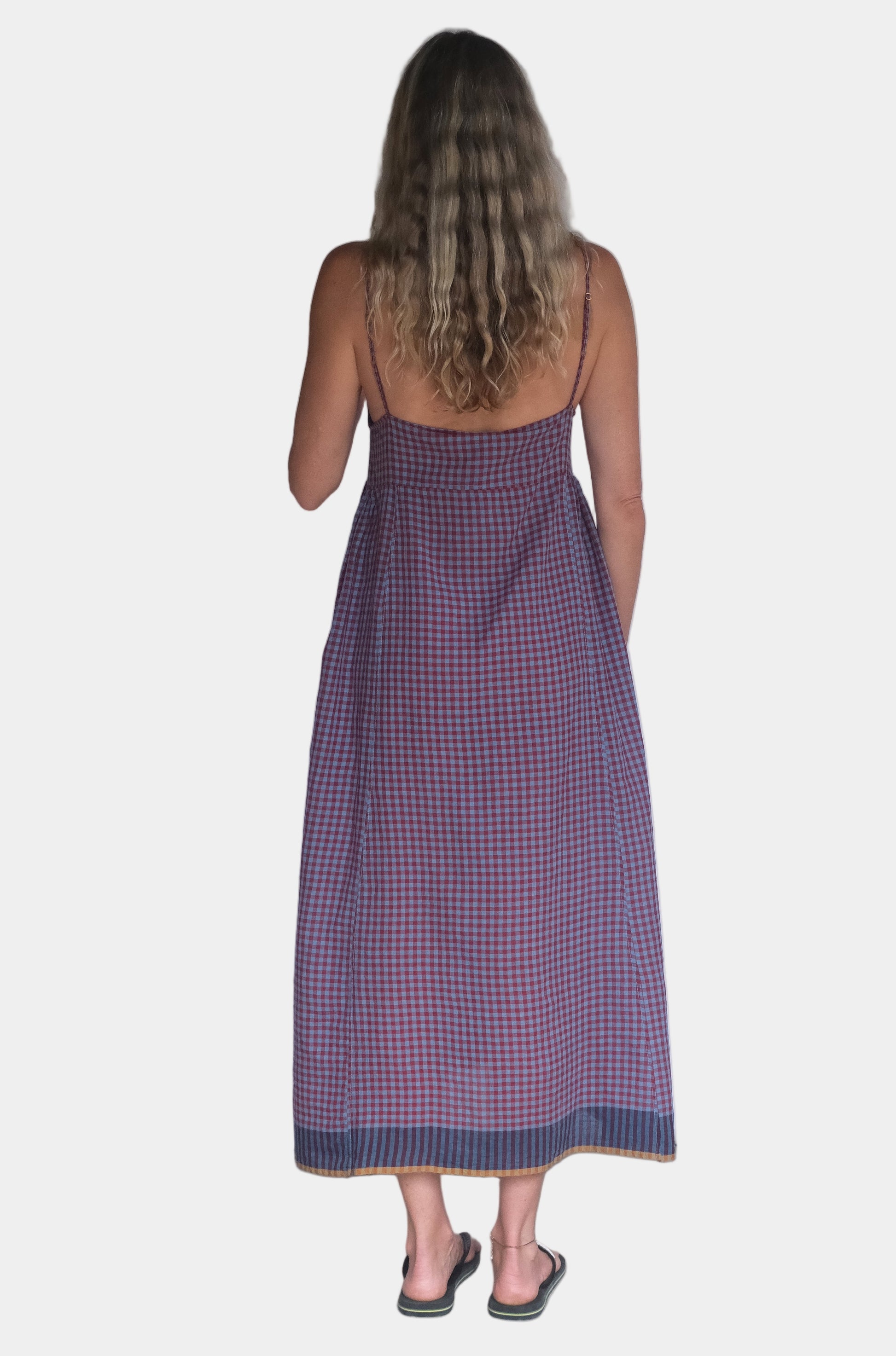 Woman wearing a purple dress standing in front of a white wall.