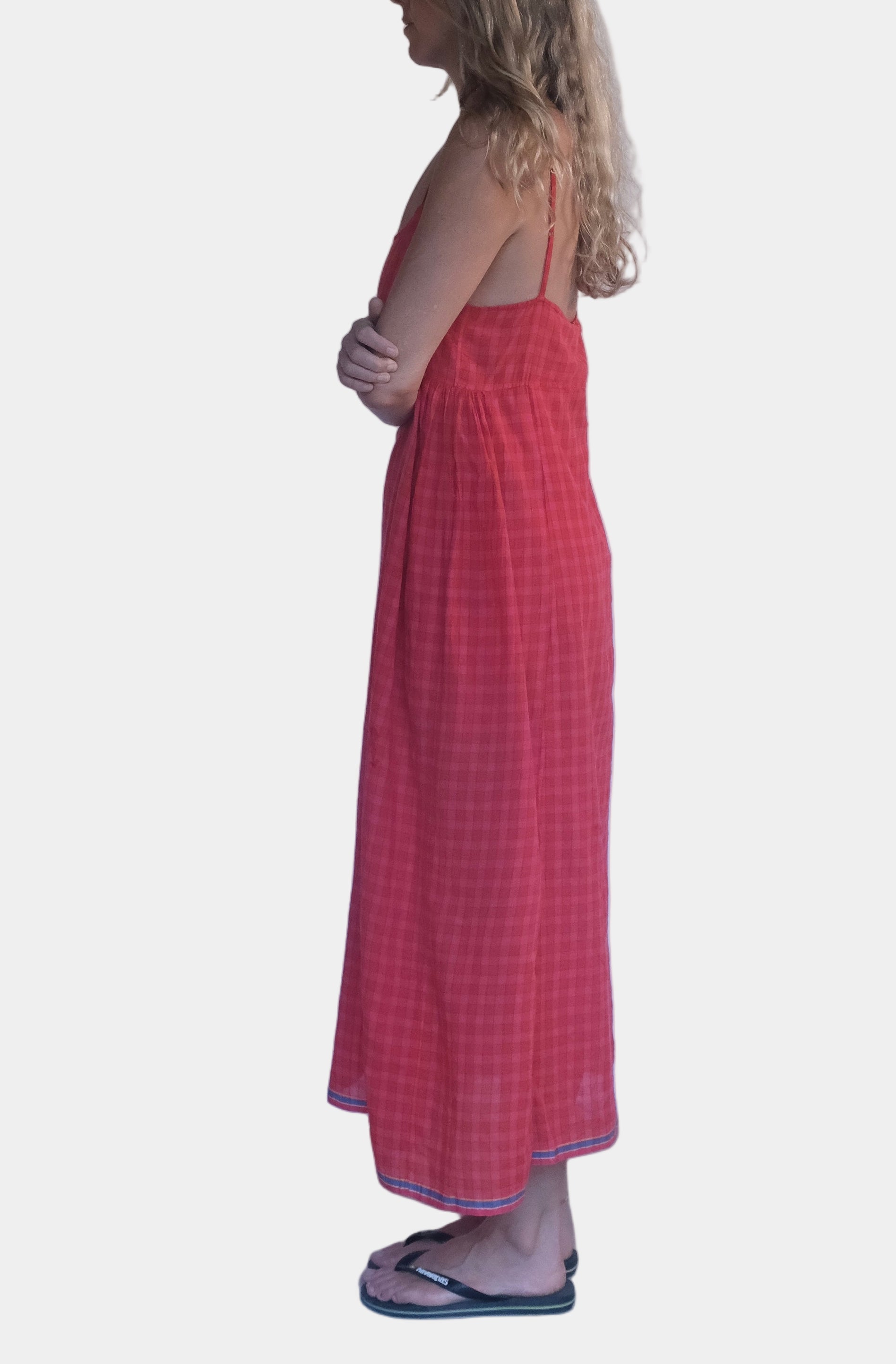 Woman in a red dress standing against a white wall.