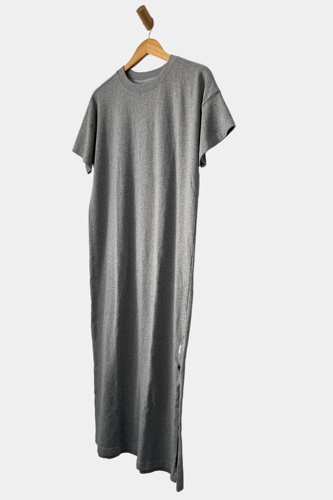 Gray t-shirt on a wooden hanger against a white wall