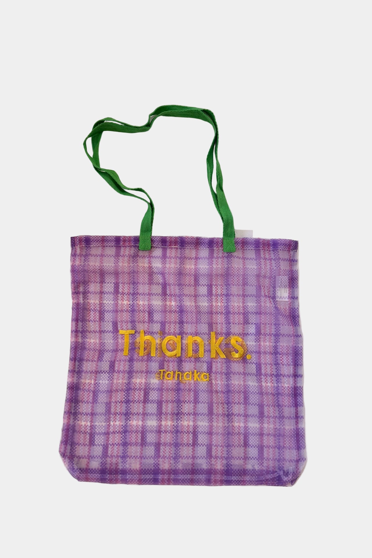 Purple checkered tote bag with green handles on a light pink background