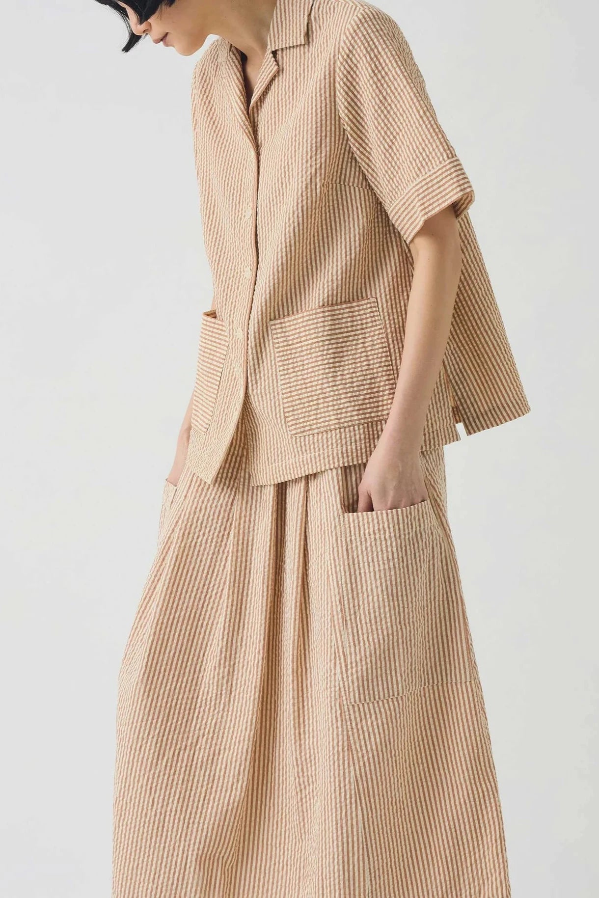 Person wearing a stripe tonal textured outfit with a shirt and skirt on a white background