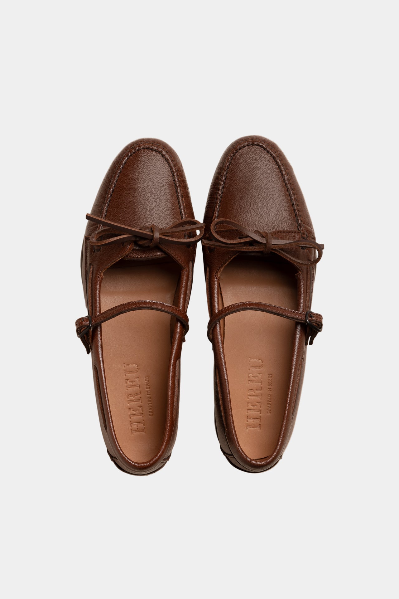 Pair of brown loafers with a brand logo on a beige background