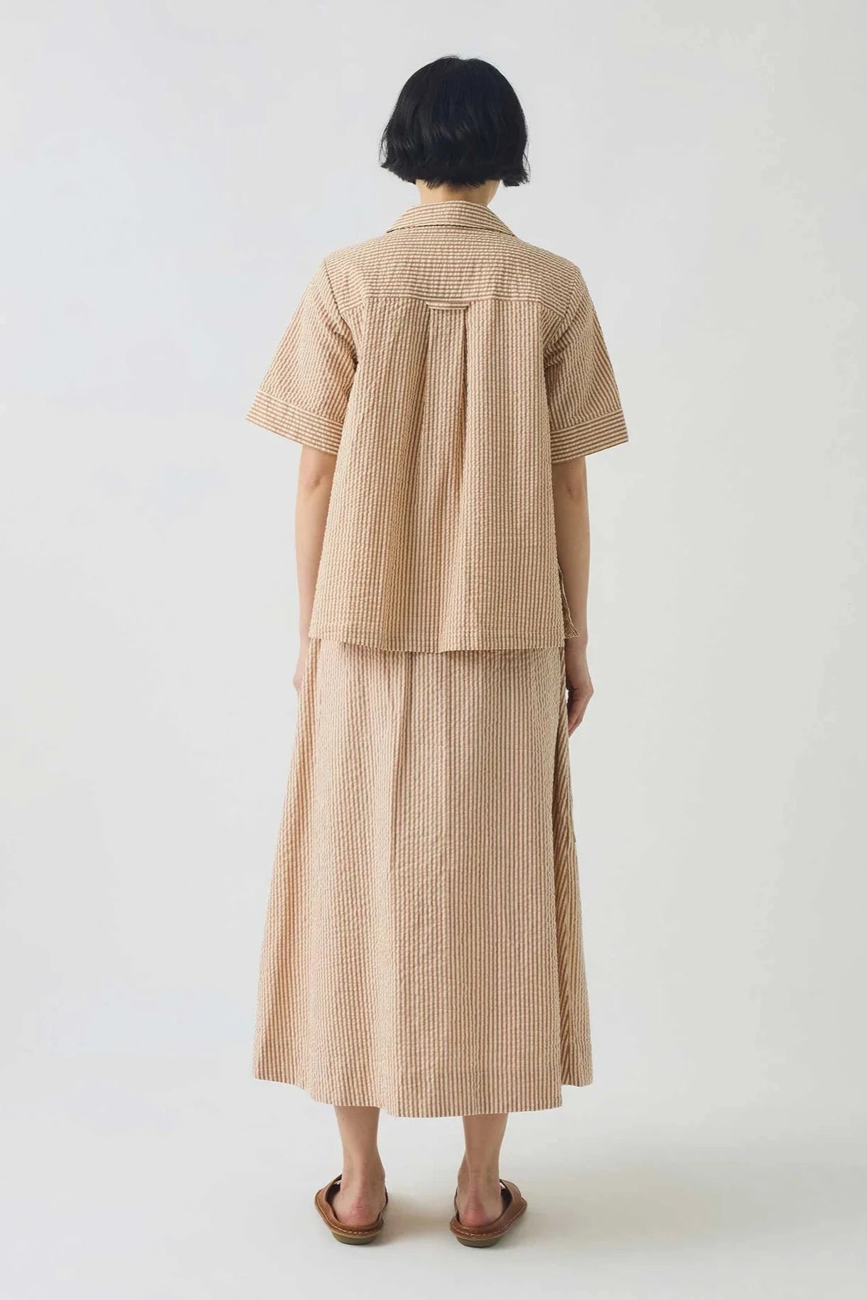 Person wearing a tonal stripe shirt and skirt outfit on a white background