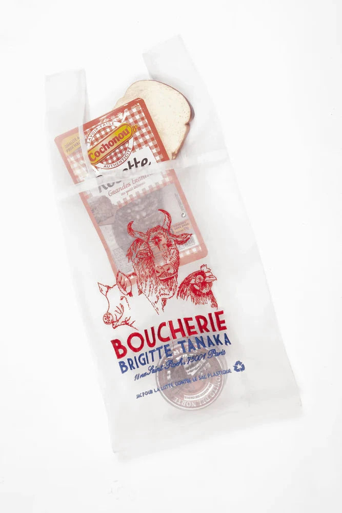 Butcher paper with red and blue text in side a organza embroidered bag with a cow illustration on a white background