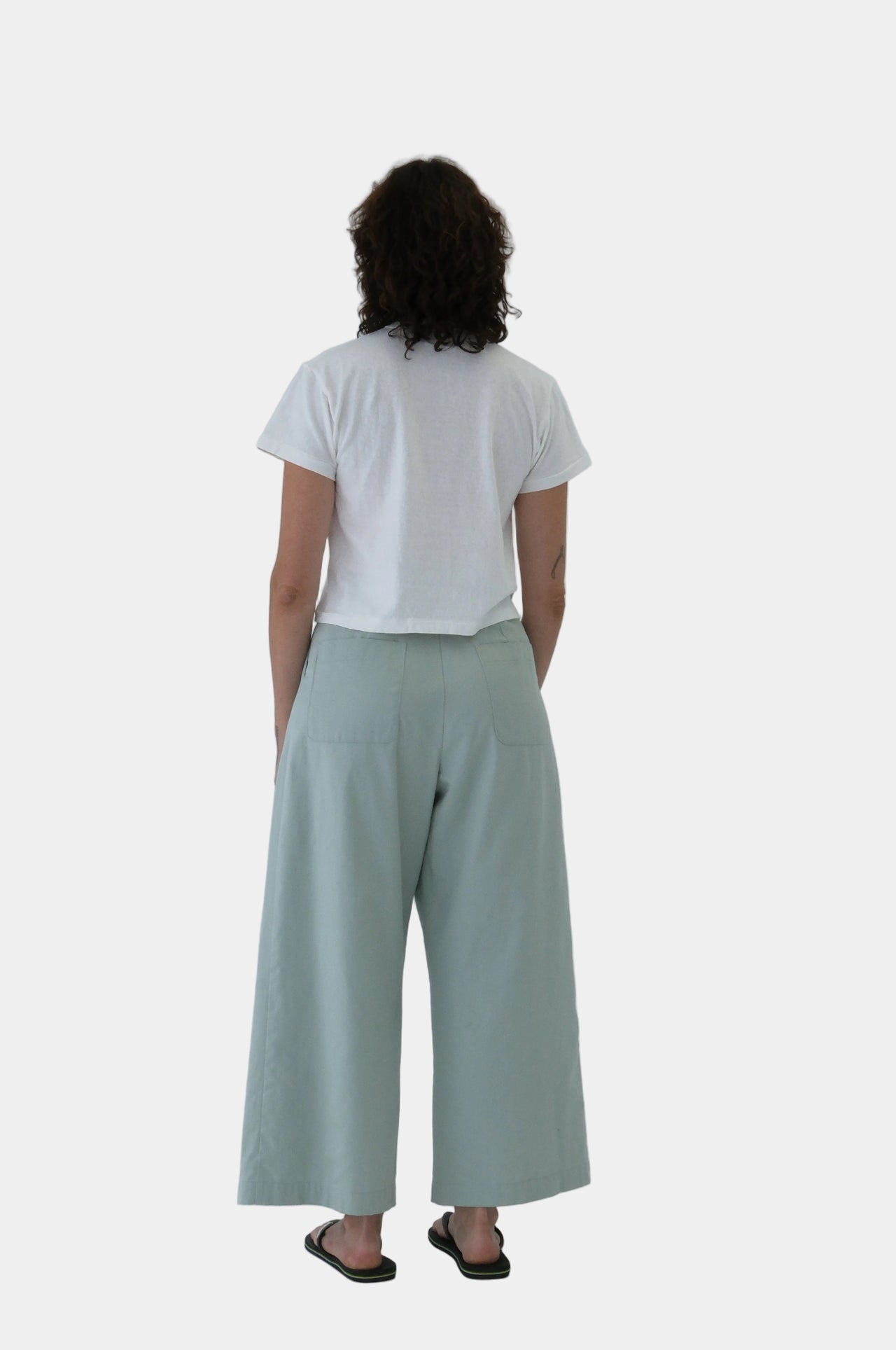 Person wearing a white t-shirt and light green pants on a white background