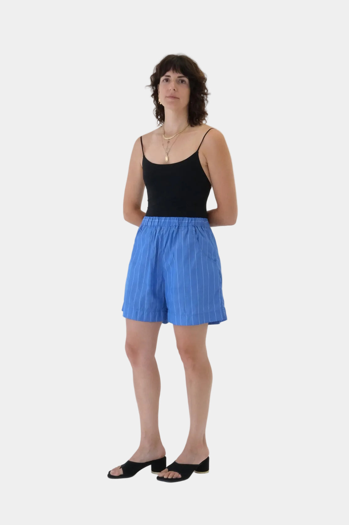Woman wearing a black top and blue shorts on a white background