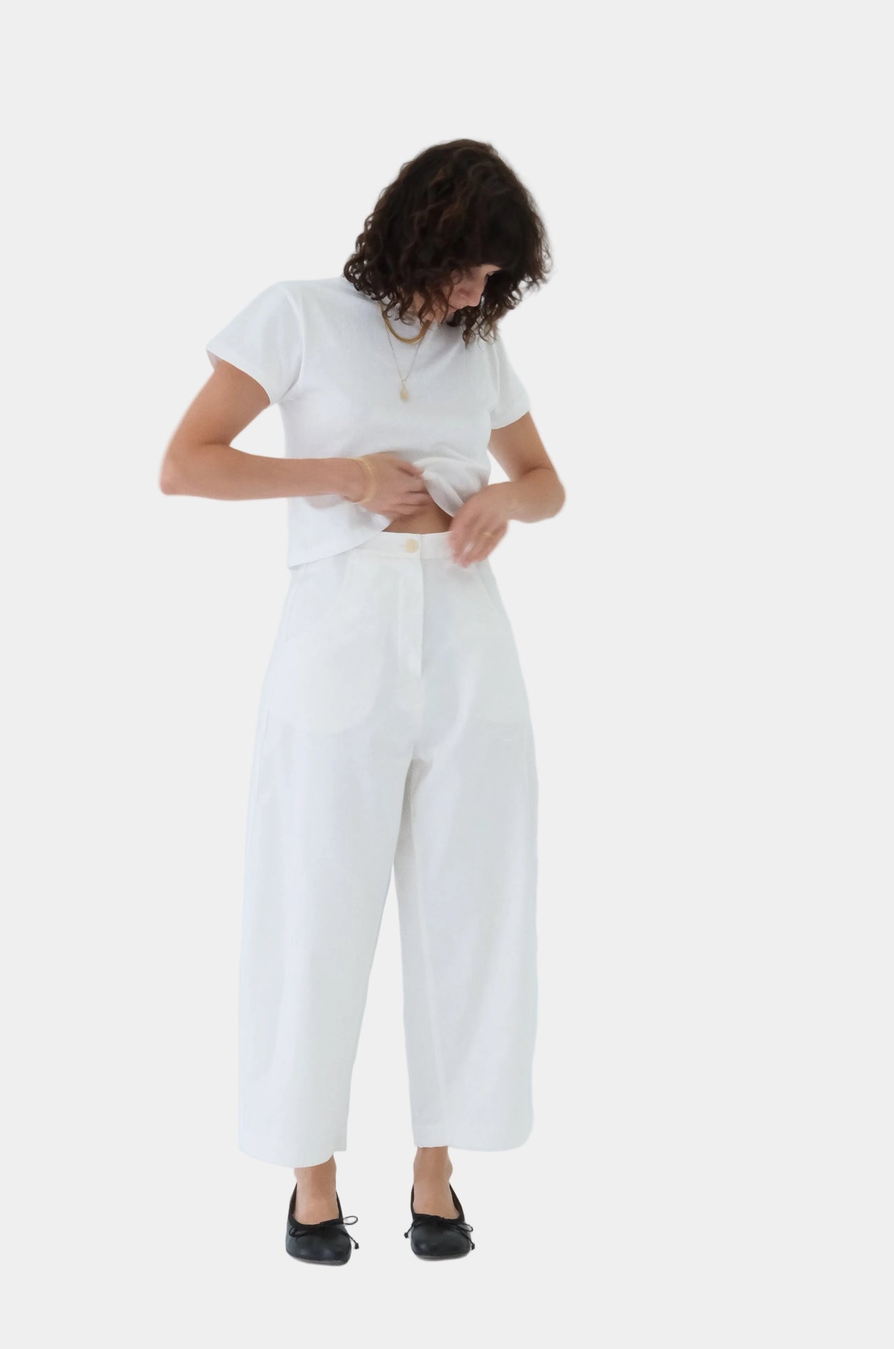 Person wearing a white t-shirt and pants on a light gray background