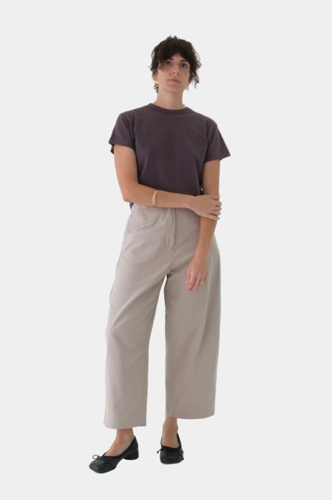 Person wearing a dark t-shirt and beige pants on a light background