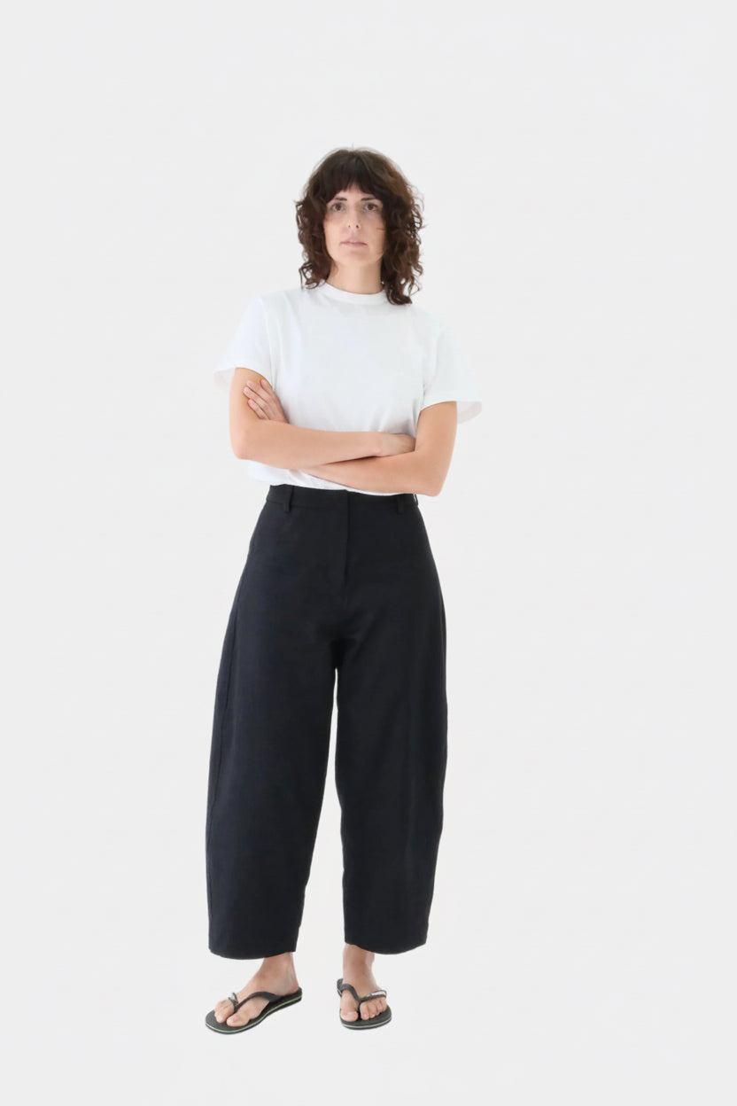 Person wearing a white t-shirt and black pants on a white background