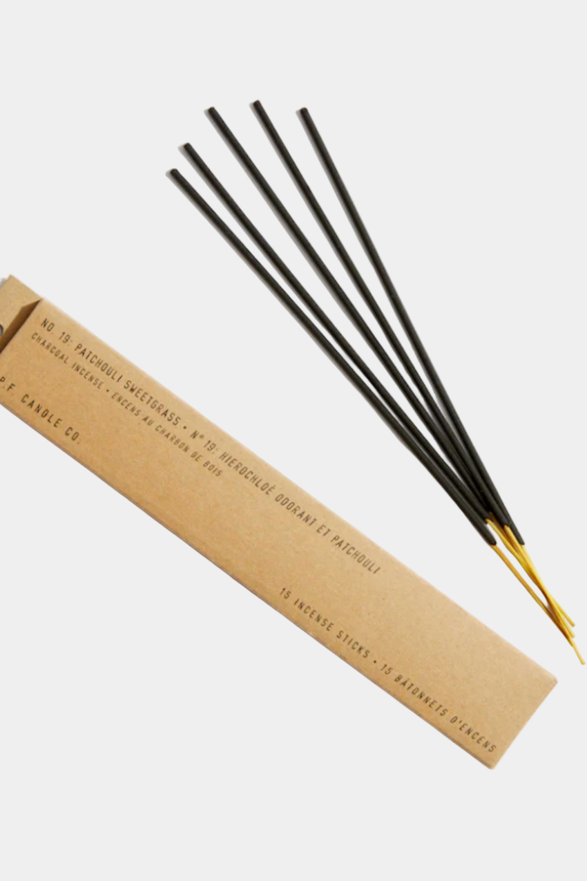 A pack of incense sticks with black and gold coloring, displayed in front of a beige background.