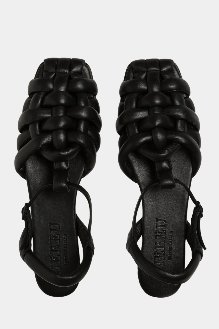 Pair of black woven sandals on a white background. Viewed from above.