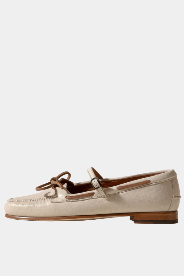 Pair of white loafers with brown bows on a white background
