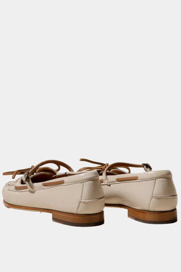 Pair of cream-colored loafers with brown soles on a white background