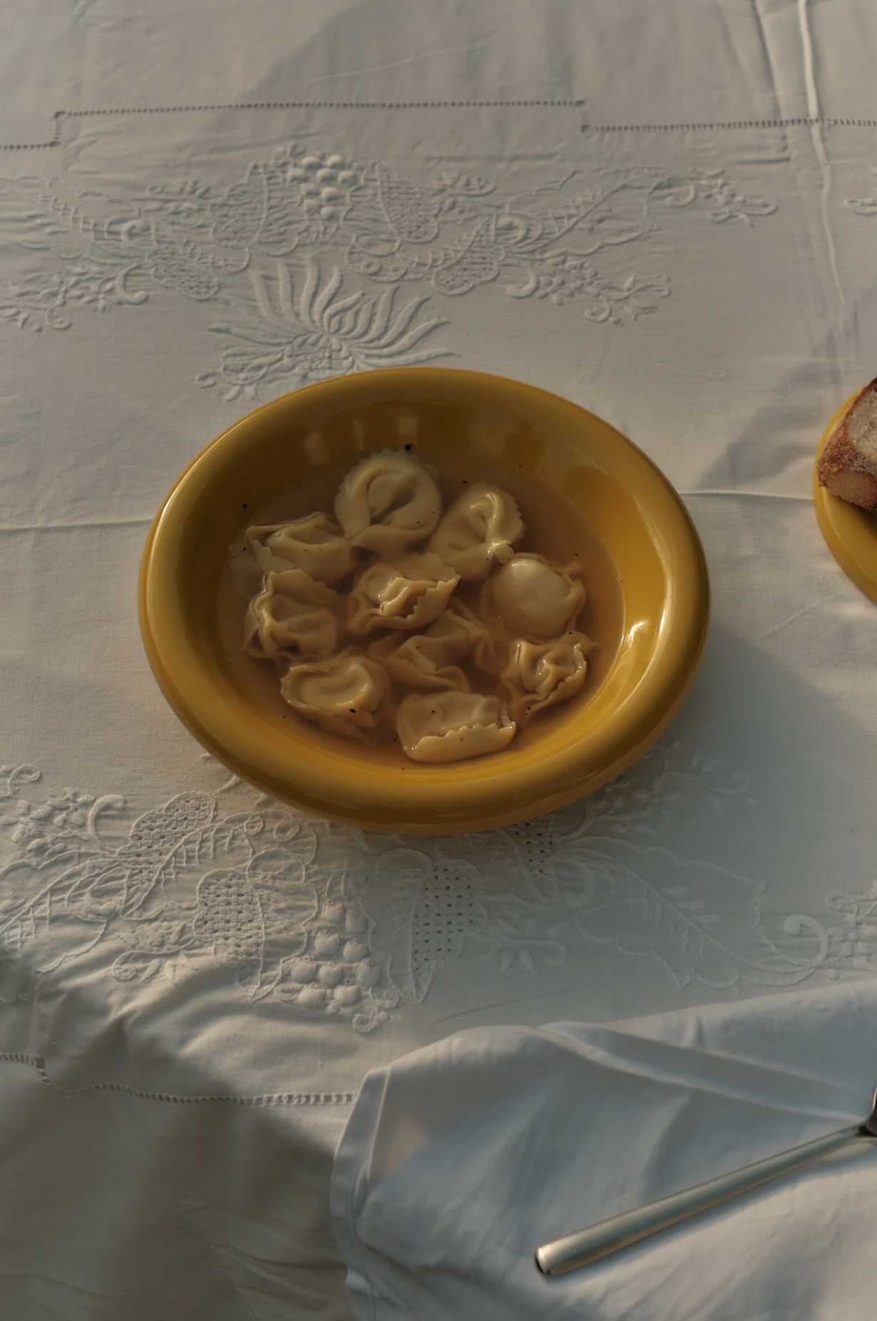 Yellow bowl with food on a white tablecloth