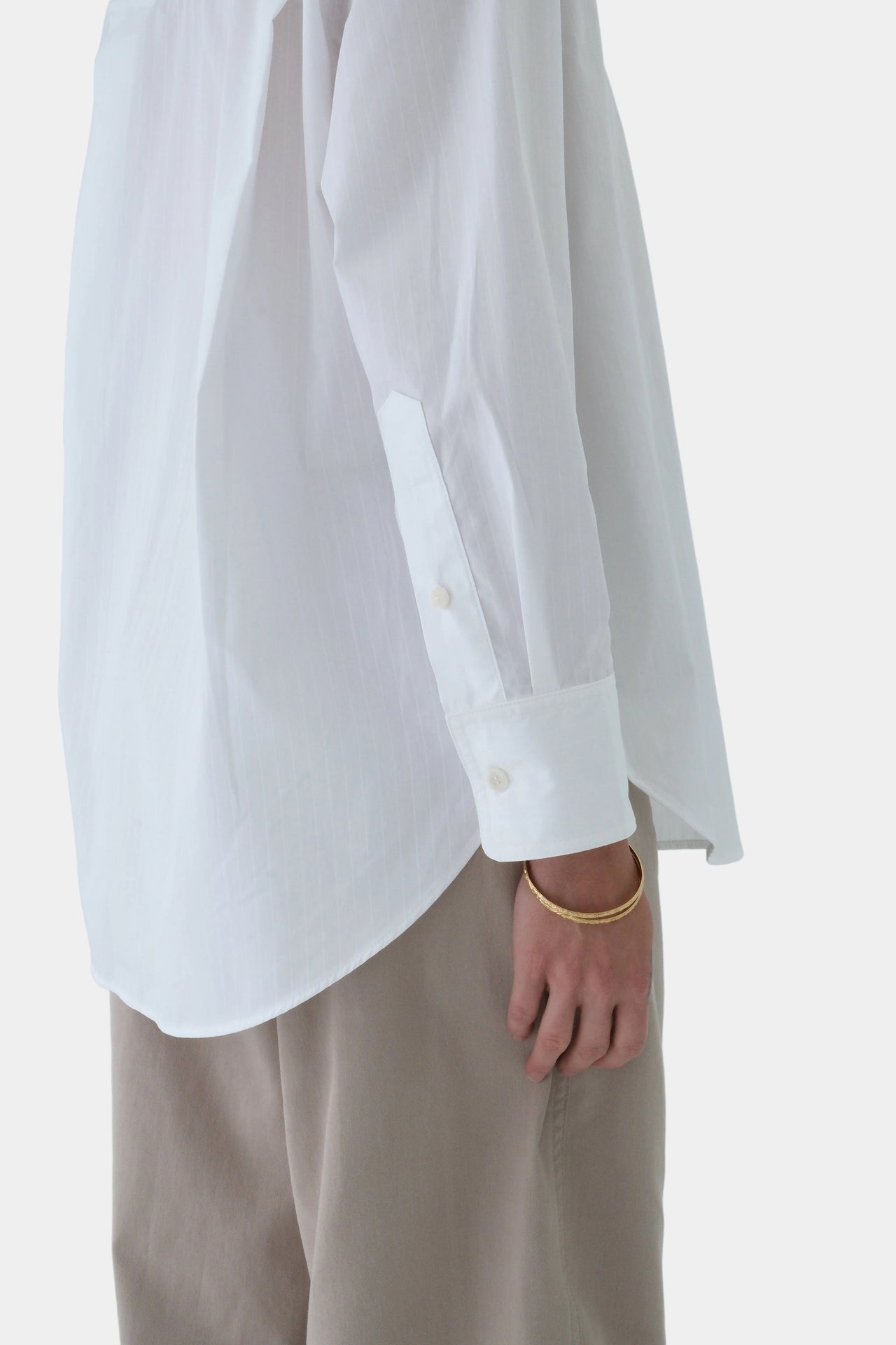 Person wearing a white shirt and beige pants on a light gray background