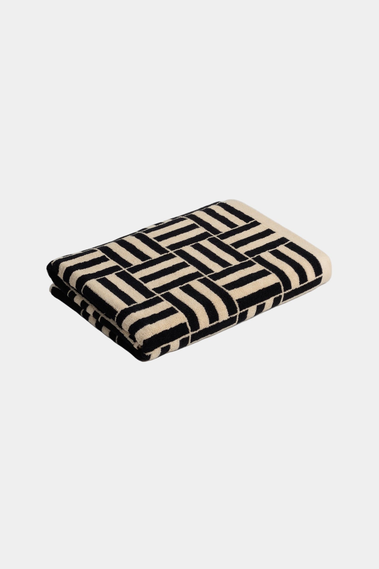 Folded towel with black and beige geometric pattern on a light gray background
