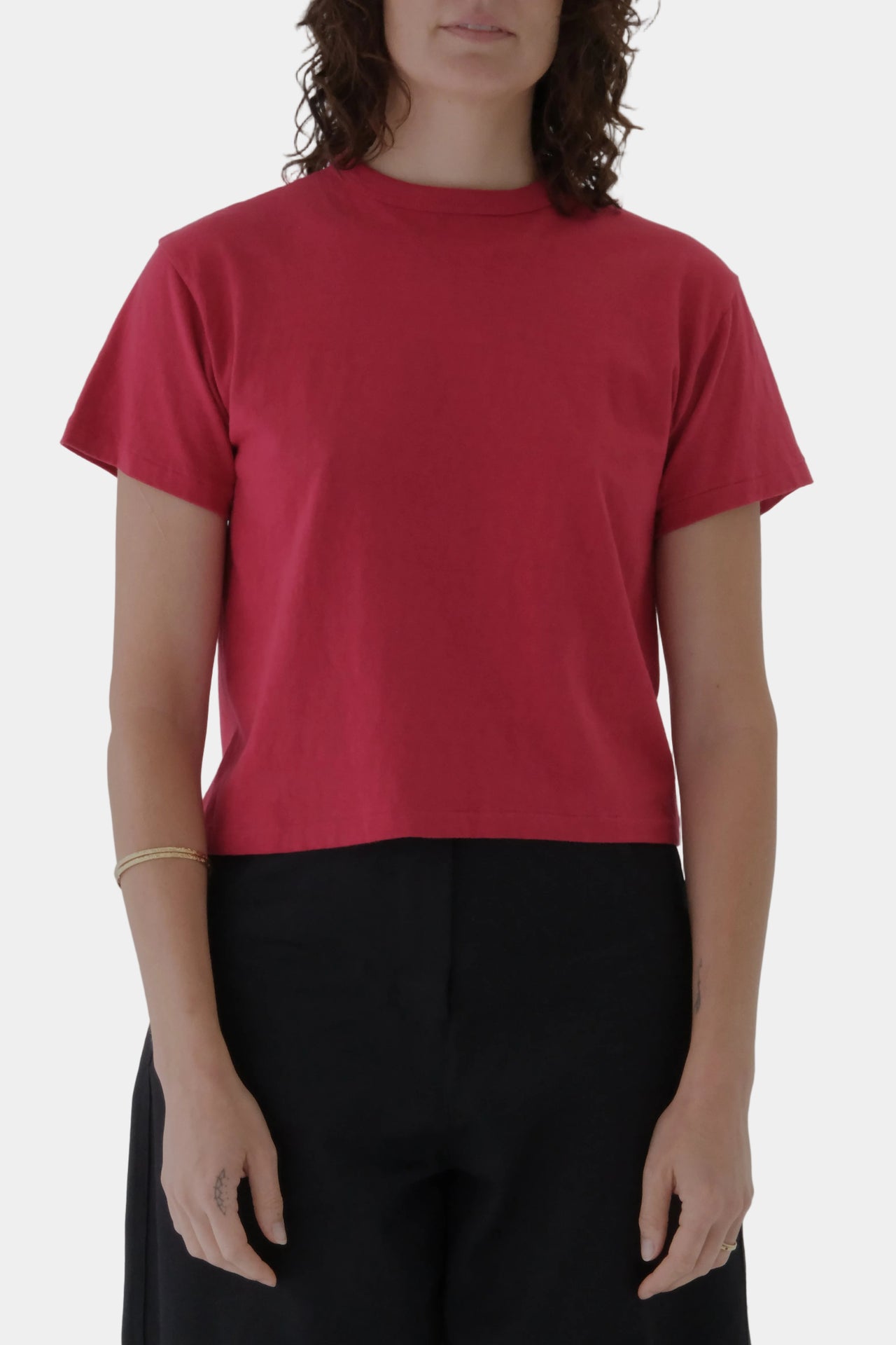 Person wearing a red t-shirt and black pants on a gray background