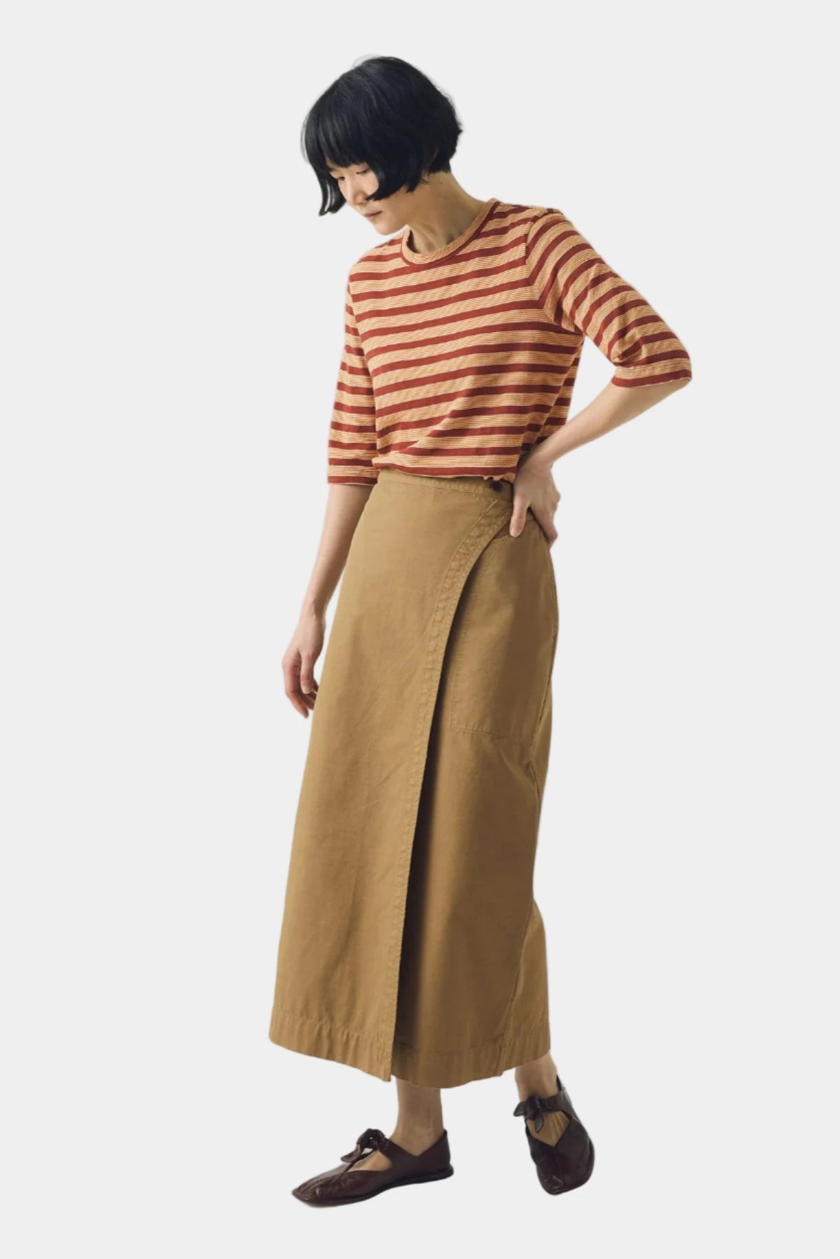 Person wearing a striped shirt and long skirt on a white background