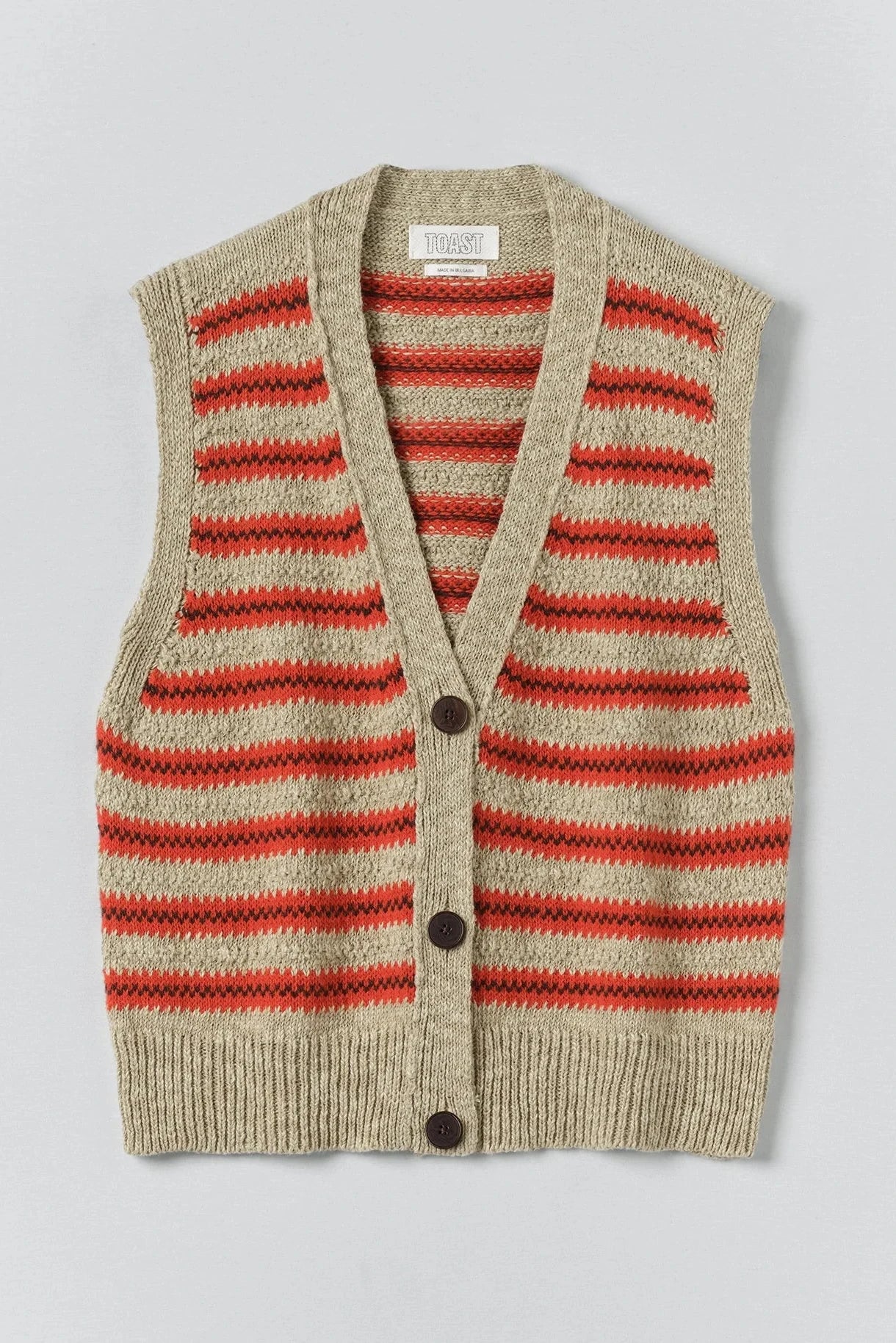 Striped sweater vest with red and beige pattern on a light gray background