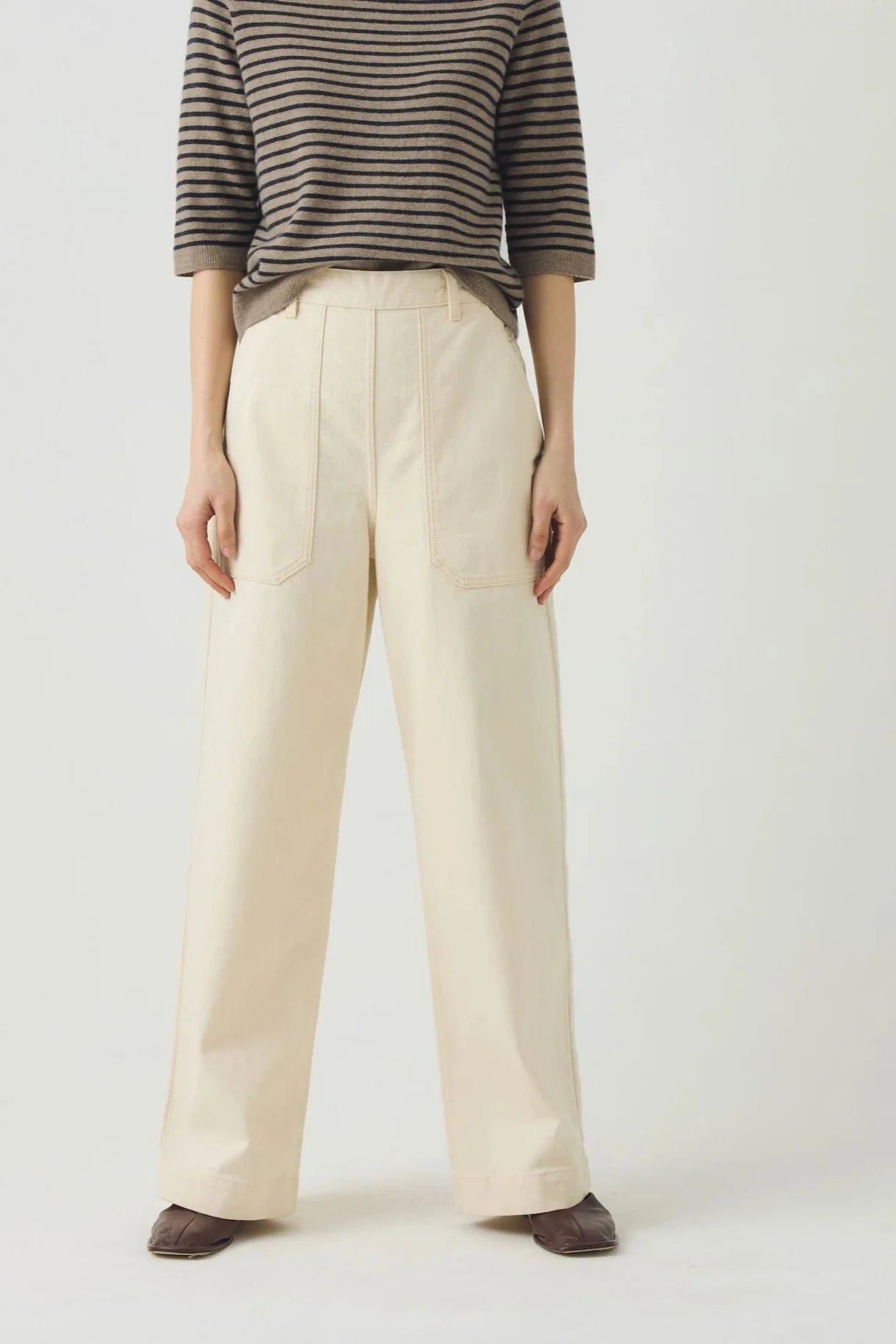 Person wearing a striped shirt and beige wide-leg pants on a plain background